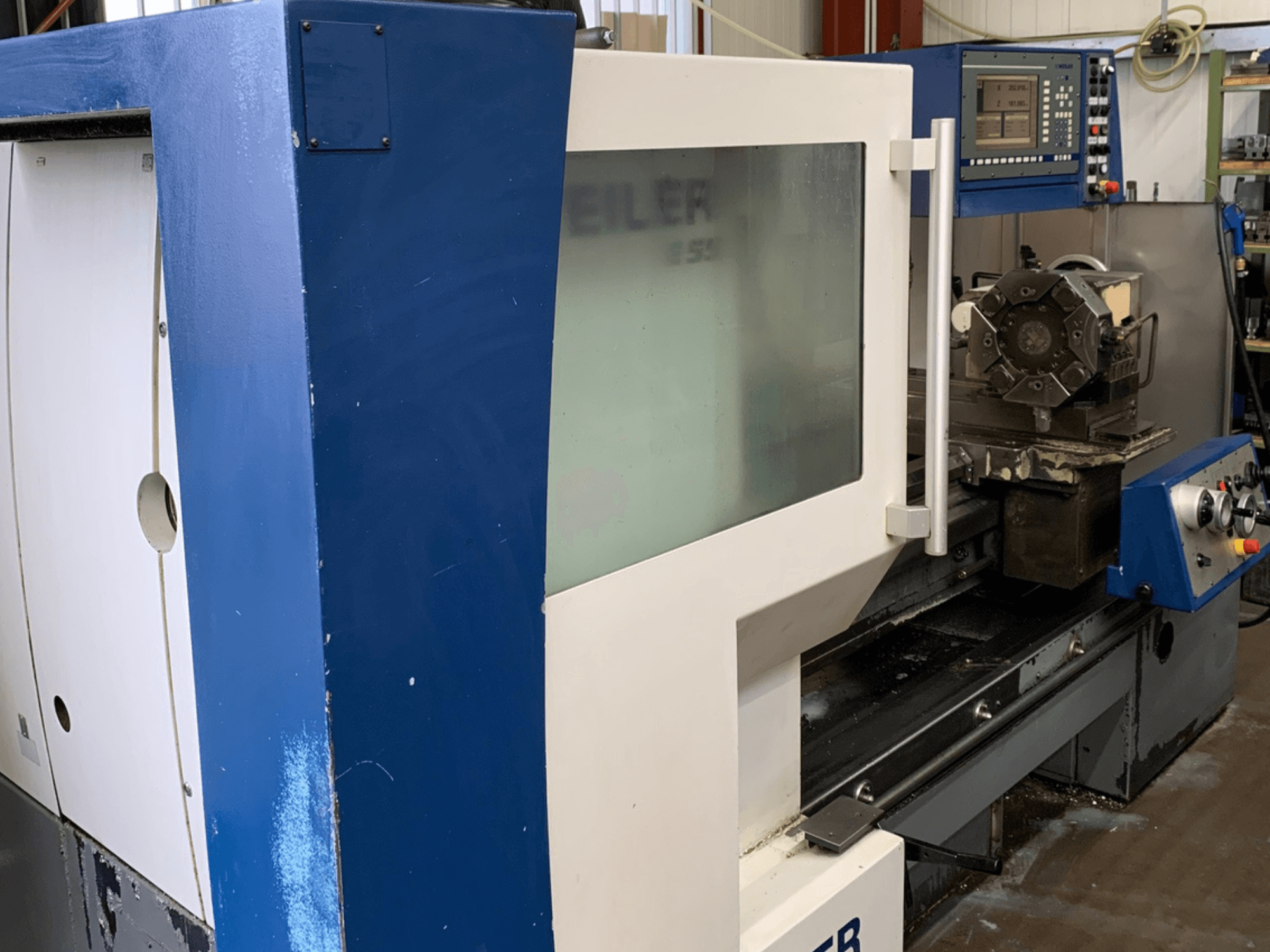 Tornio orizzontale Weiler E55X1000, vista laterale che mostra il pannello di controllo e la configurazione degli utensili da taglio.