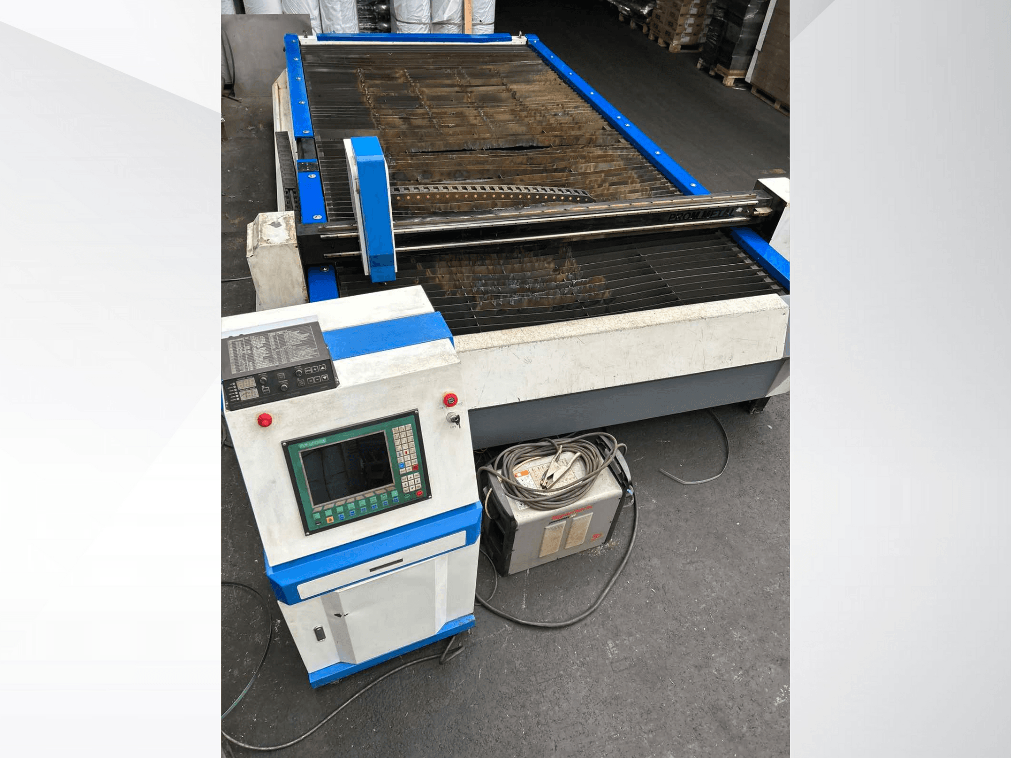 Macchina per il taglio al plasma CNC con pannello di controllo, vista frontale, con accenti blu e cavi sul pavimento.