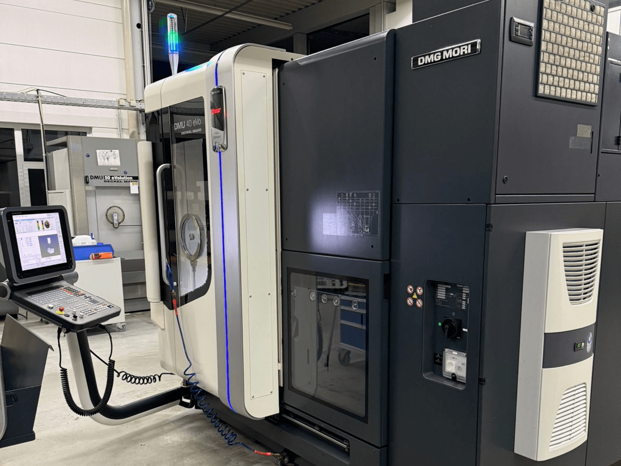 Macchina DMG MORI DMU 40 eVo, vista frontale che mostra i comandi, gli indicatori LED e il design elegante che enfatizza le caratteristiche industriali.
