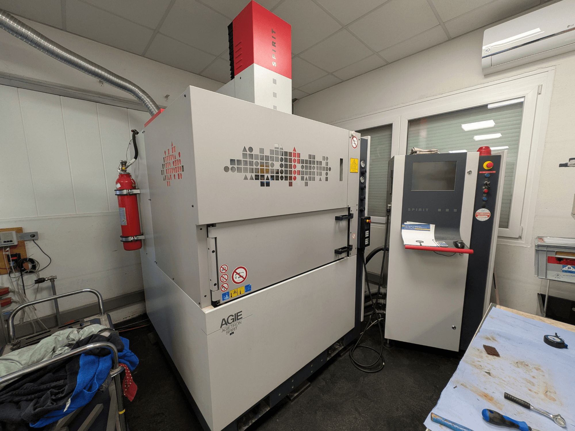 Macchina per elettroerosione a tuffo AGIE AGIETRON SPIRIT 3, vista laterale, con pannello di controllo ed estintore.