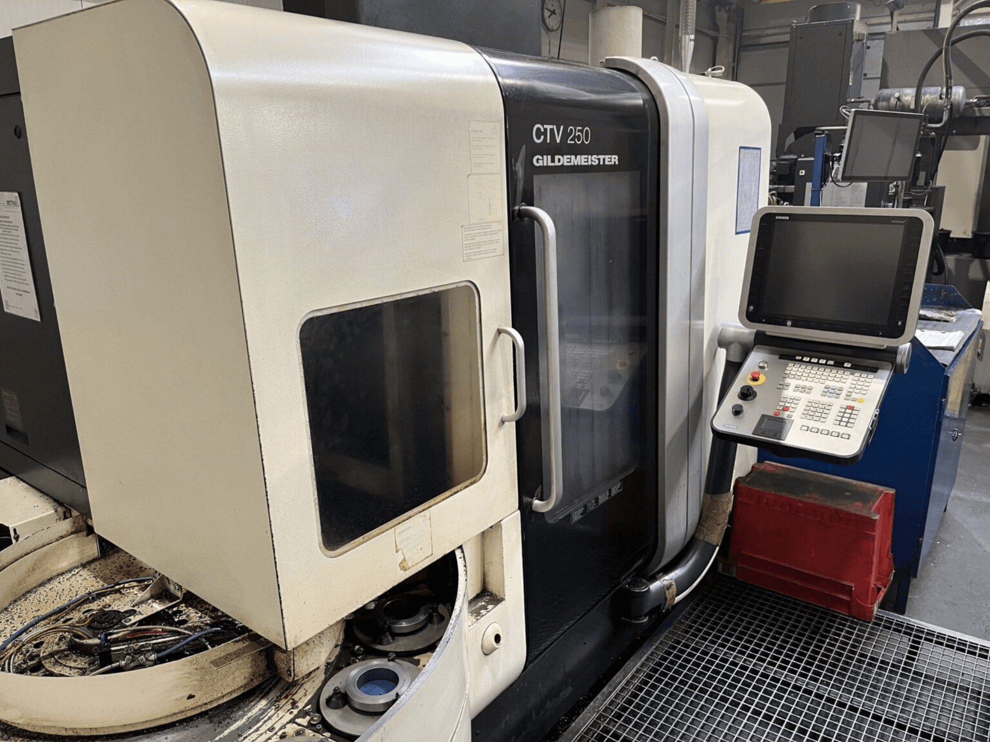 Tornio verticale DMG CTV-250 visto frontalmente, con pannello di controllo e area di lavoro con utensili.