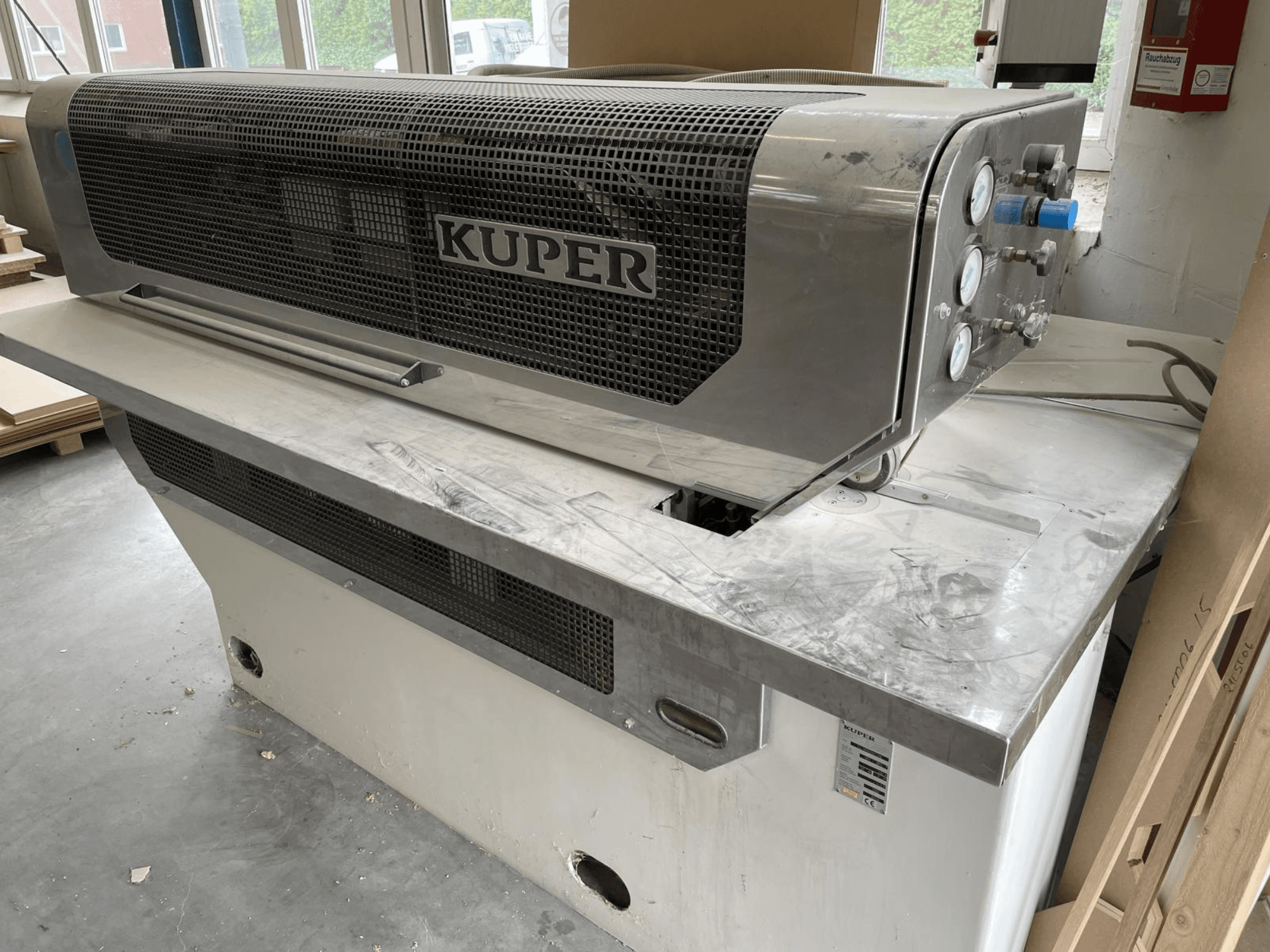 Ghigliottina per impiallacciatura KUPER FLI, vista frontale, con corpo in acciaio inox, indicatori e area di taglio pulita su un banco di lavoro.