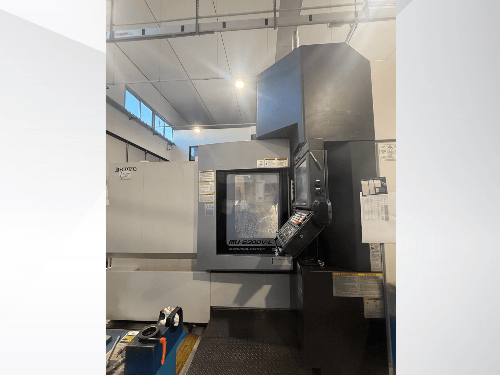 Macchina CNC Okuma MU-6300V-L vista dal davanti, con il pannello di controllo e le etichette di sicurezza.