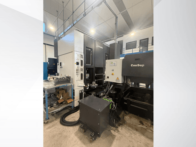 Centro di lavoro Okuma con unità ConSep, vista laterale, con visualizzazione dei comandi e dell'allestimento industriale, compreso il contenitore dei trucioli metallici.