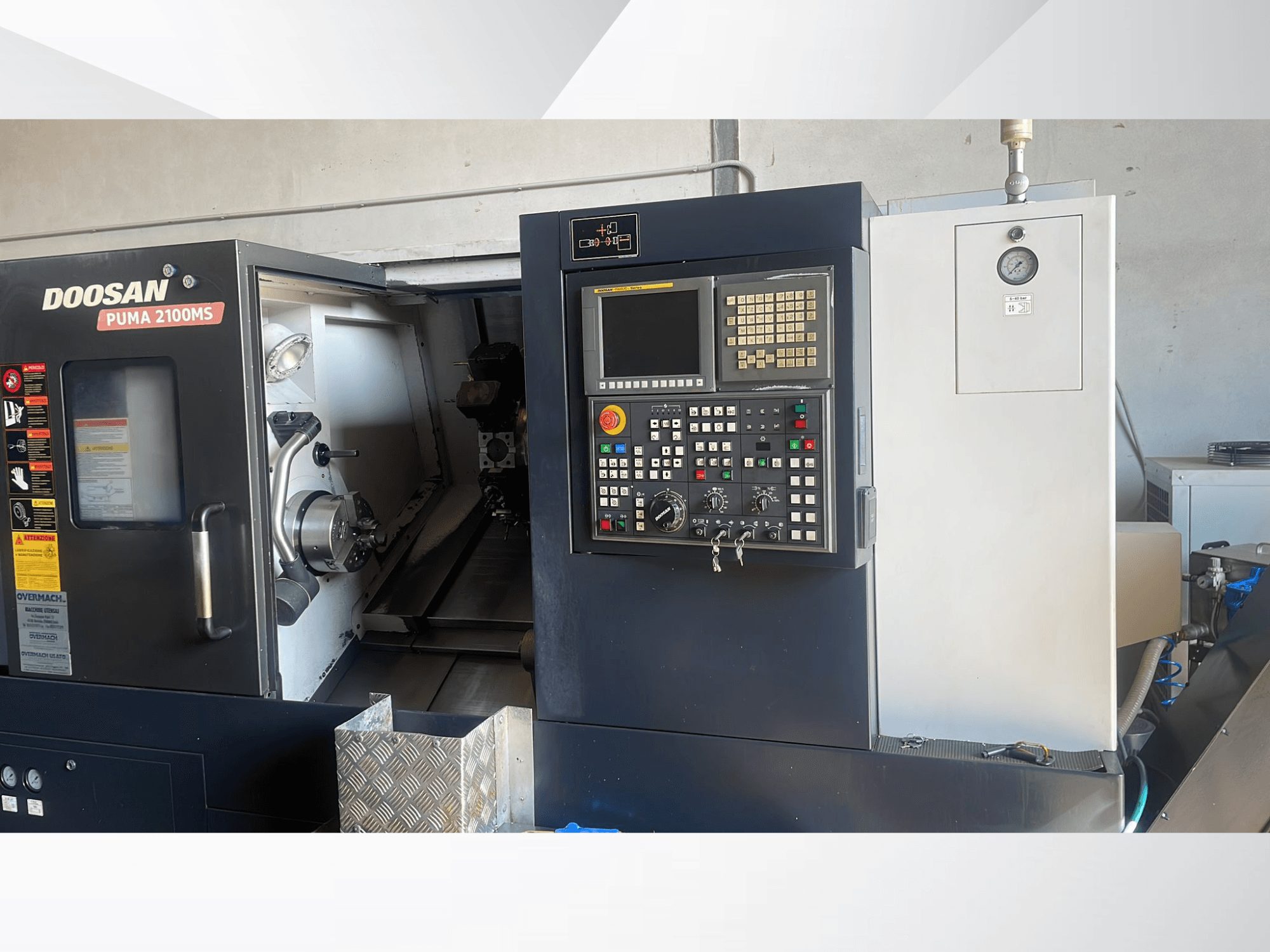 Vista frontale del tornio orizzontale DOOSAN PUMA 2100MS, con in primo piano il pannello di controllo, il mandrino e gli utensili da taglio all'interno della camera.