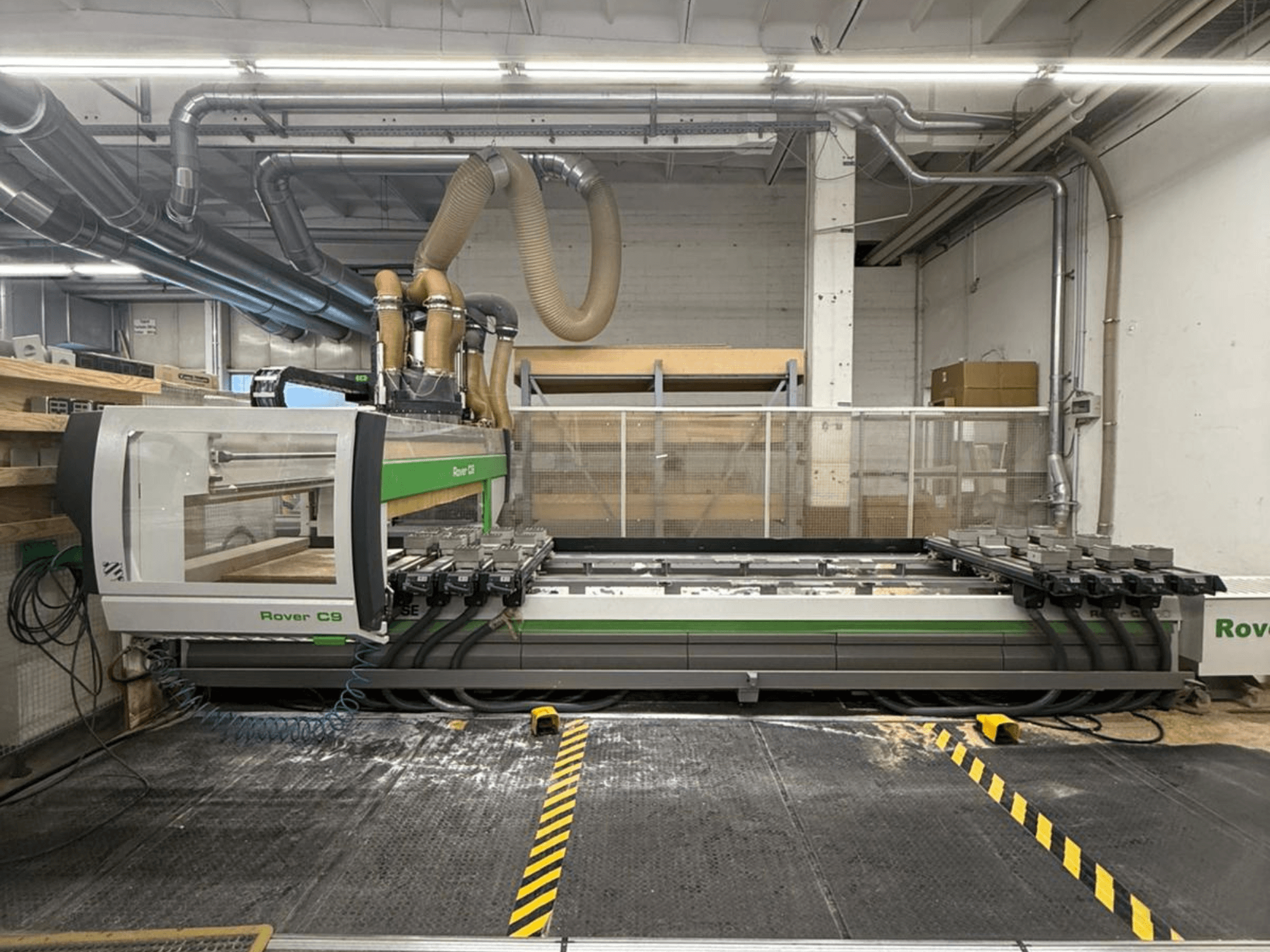 Macchina CNC Rover C9 in un'officina, vista frontale, con teste di taglio multiple e sistema di aspirazione visibile.