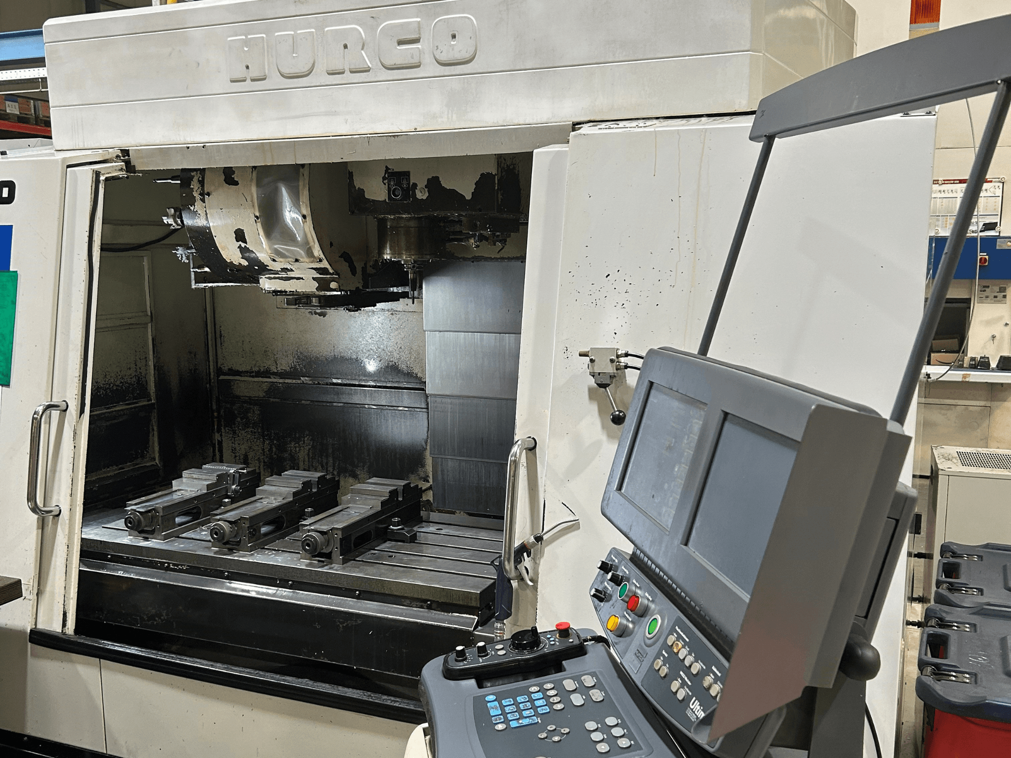 Fresatrice CNC Hurco, vista frontale, con quattro portautensili sul tavolo e un pannello di controllo con doppio schermo e pulsanti.