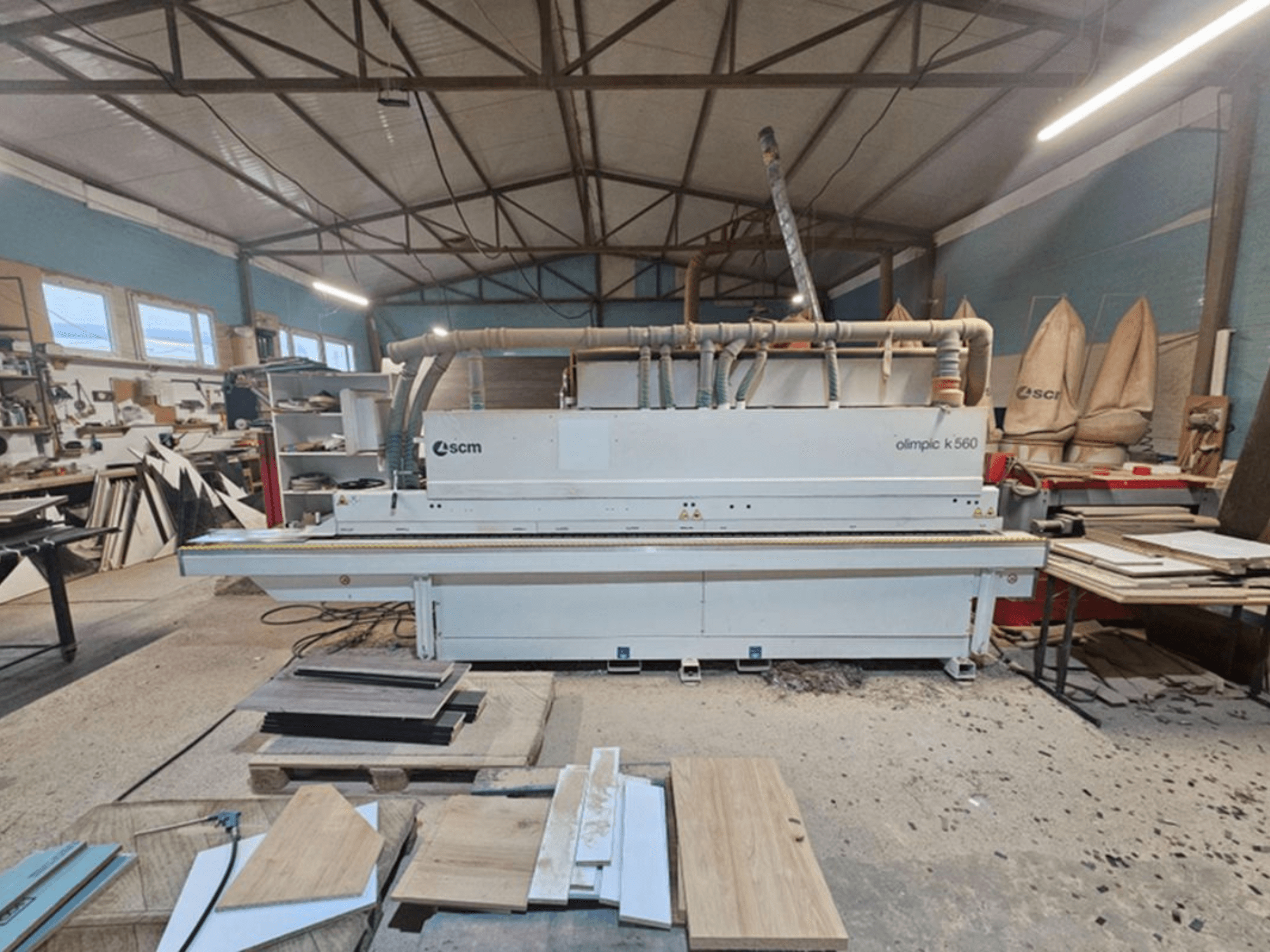 Bordatrice SCM Olimpic K 560 in un’officina, vista frontale; tra le caratteristiche visibili figurano i rulli di avanzamento e il sistema di aspirazione.