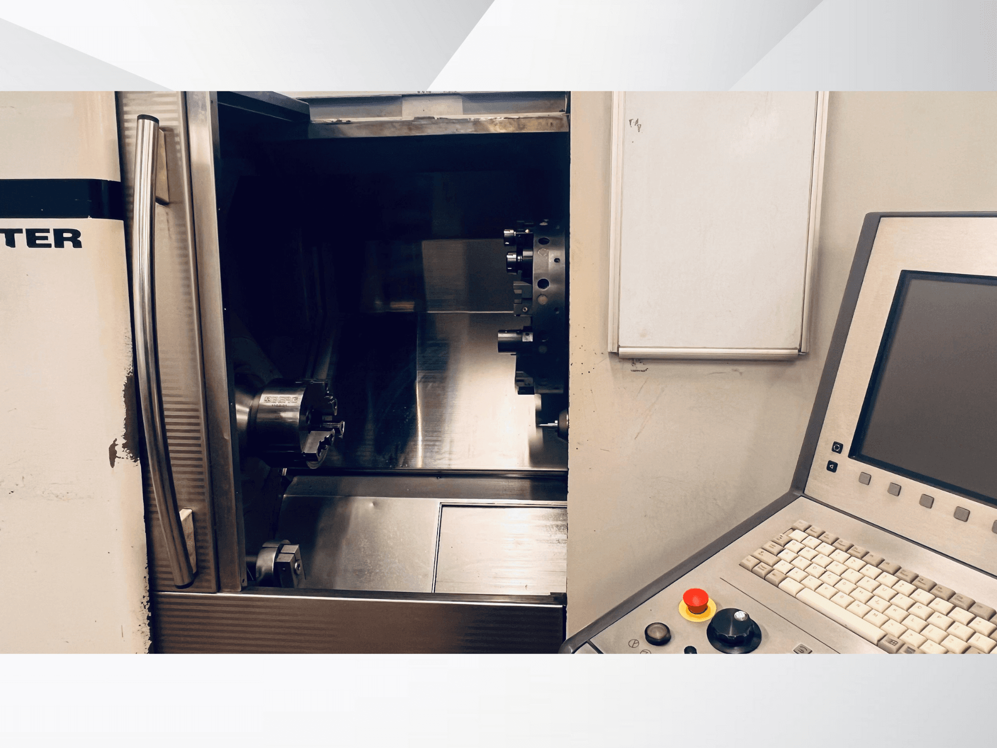 Vista frontale della macchina CNC che mostra la camera aperta e il pannello di controllo con tastiera e pulsante di arresto di emergenza.