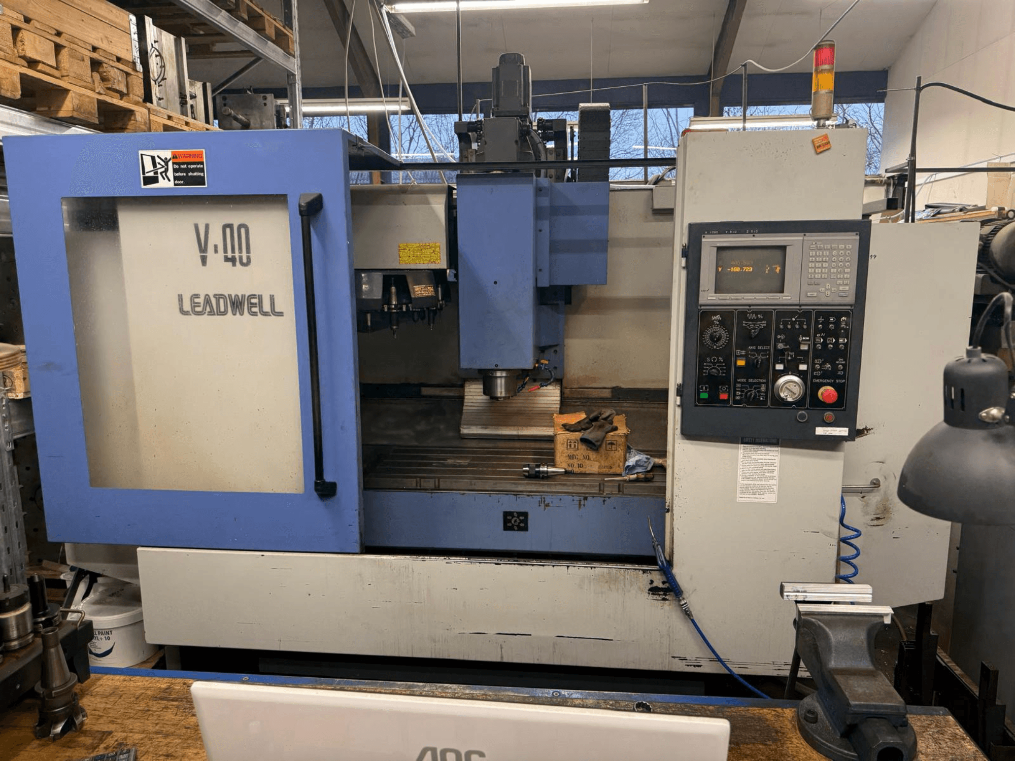 Fresatrice CNC LEADWELL V-40, vista frontale, con pannello di controllo, utensili da taglio e morsa su un banco di lavoro.