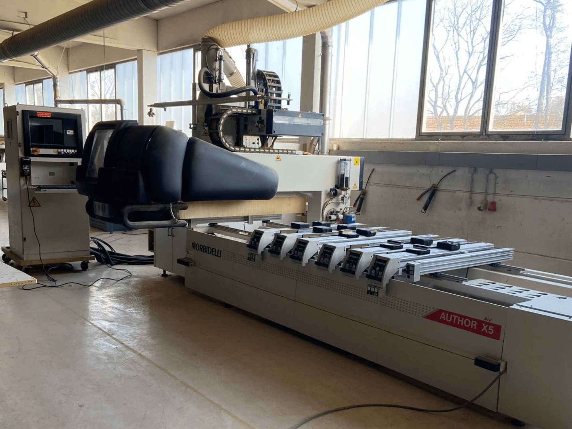 Centro di lavorazione del legno a CNC MORBIDELLI Author X5 in un'officina, che mostra il pannello di controllo e l'area di lavorazione da una vista laterale.