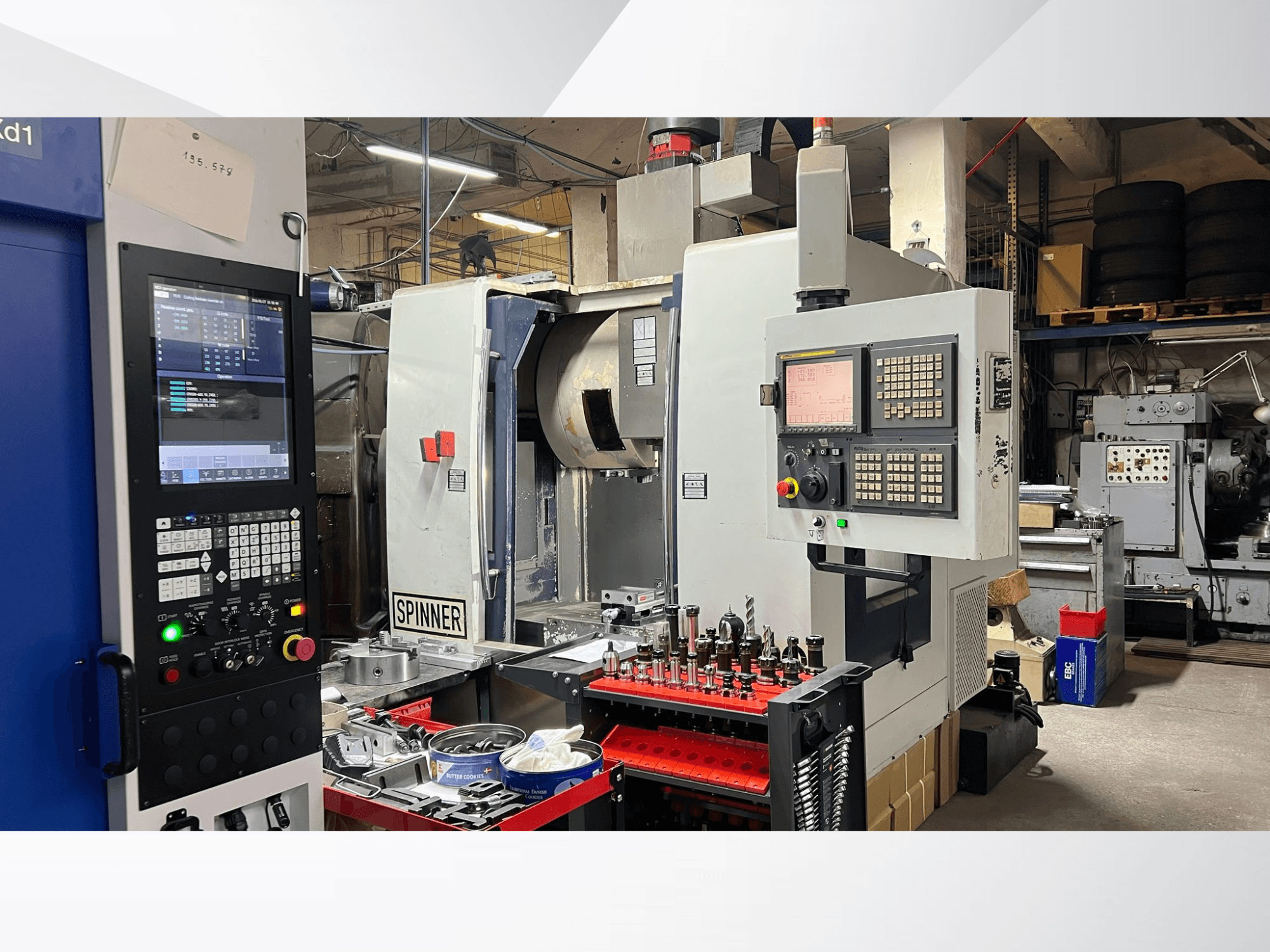 Macchina CNC con pannello di controllo, utensili e pezzi visibili, vista da un'angolazione frontale in un ambiente di officina.