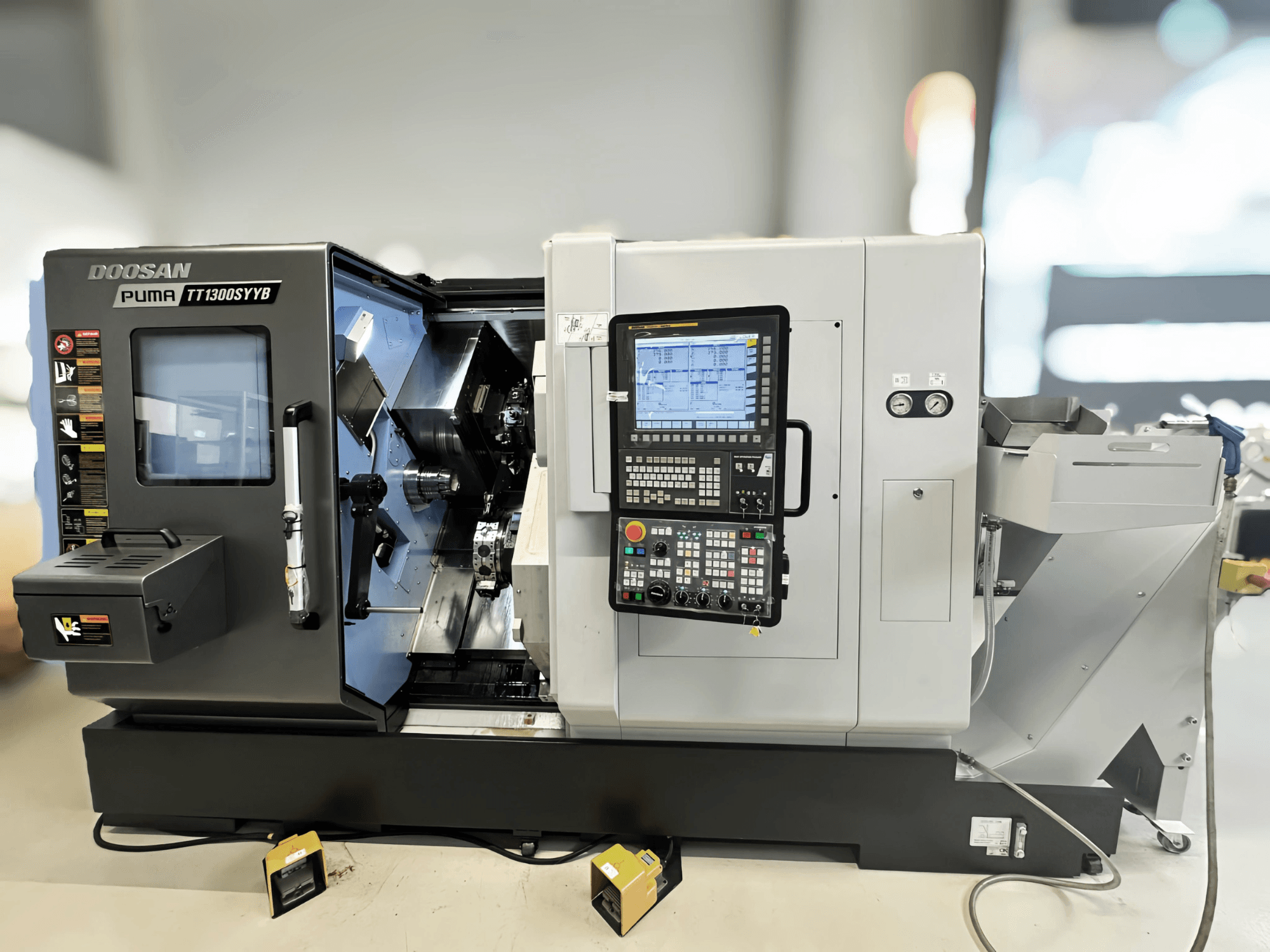 Centro di fresatura Doosan Puma TT1300SYYB in vista laterale, con pannello di controllo e interno macchina con utensili visibili.