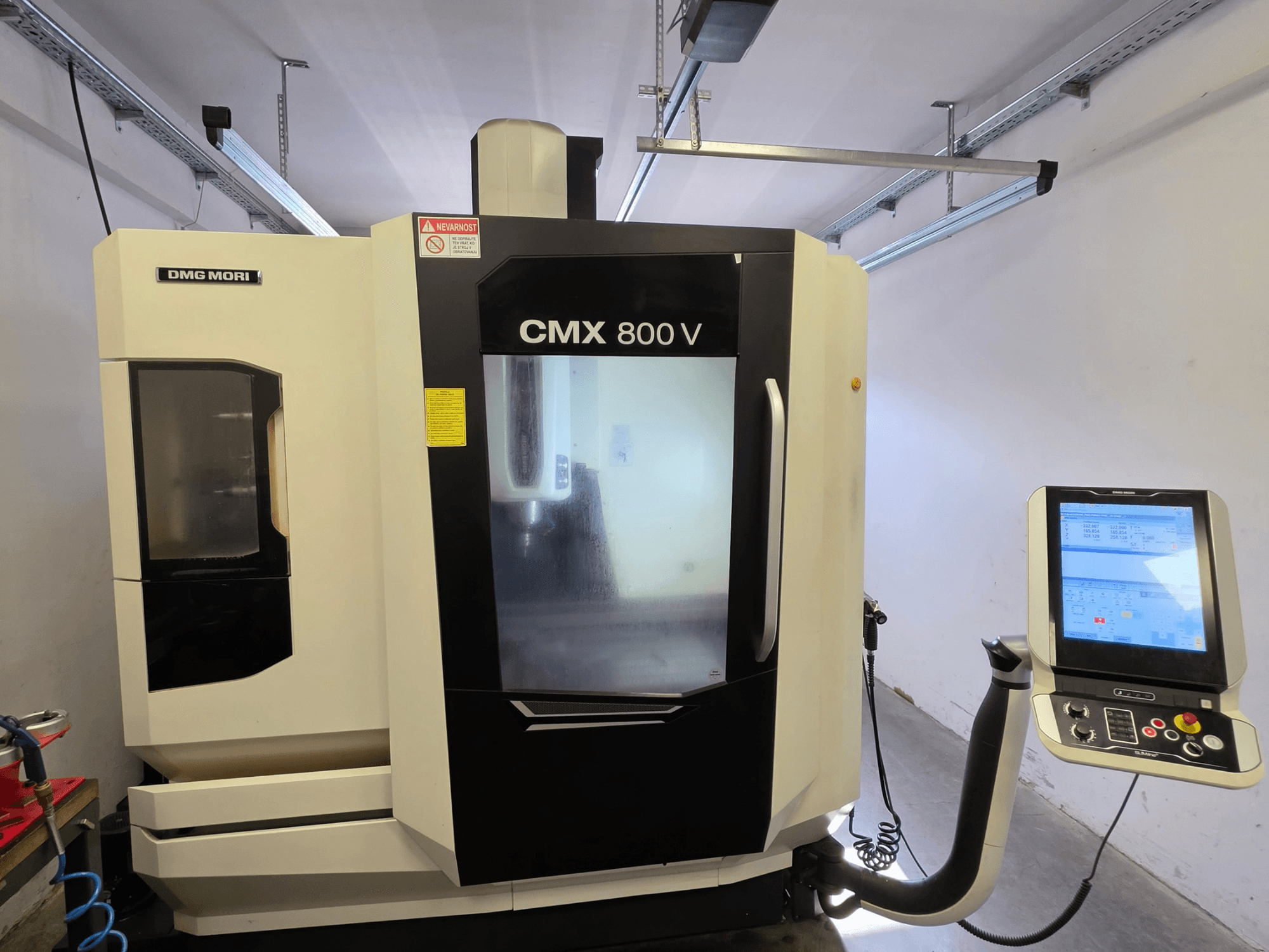 Centro di lavorazione verticale DMG MORI CMX 800V, vista frontale, dotato di pannello di controllo touchscreen e chiara segnaletica di sicurezza.