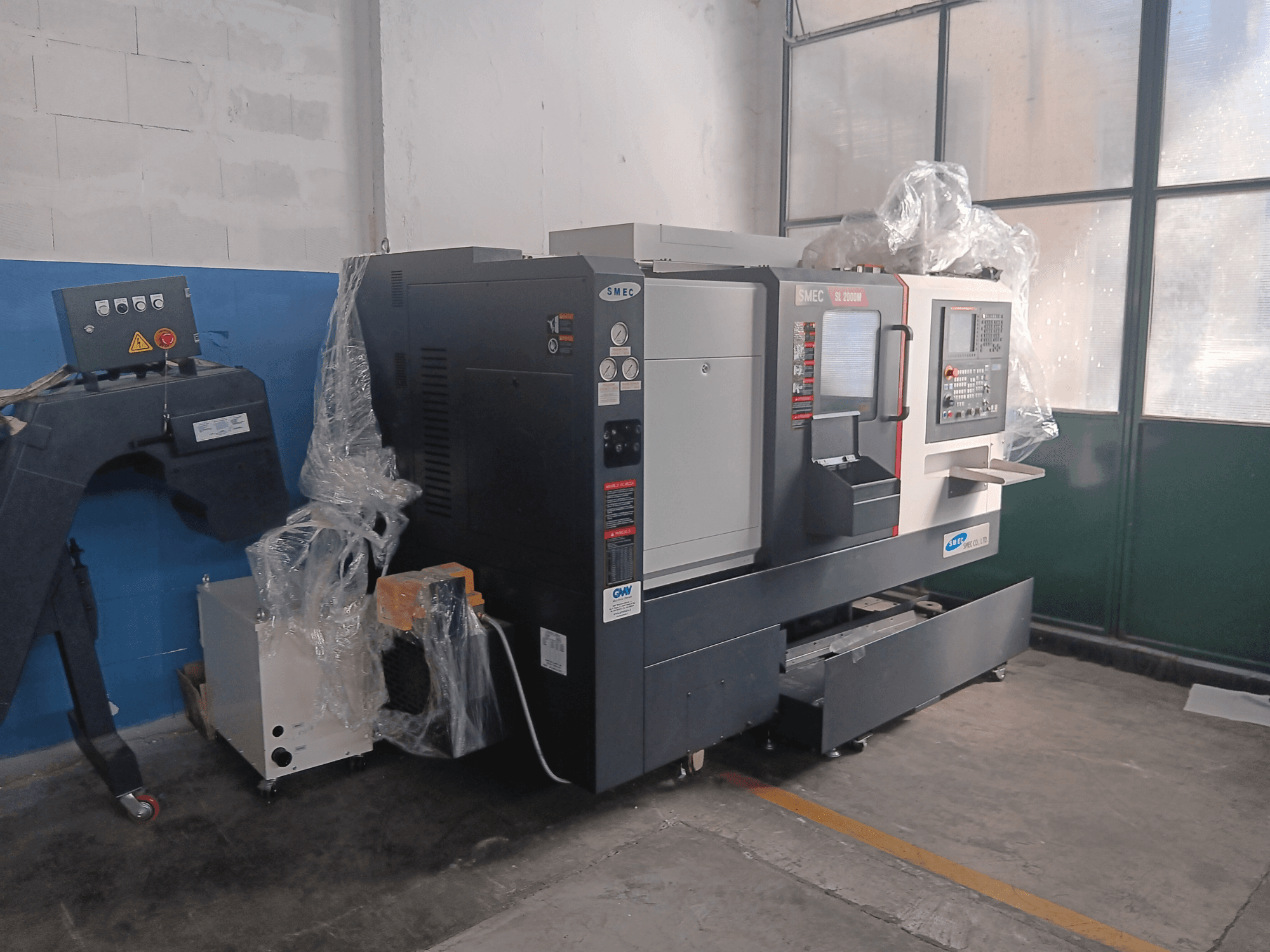 Tornio orizzontale SMEC SL2000M B TYPE, vista laterale, con pannello di controllo e involucro protettivo in plastica.