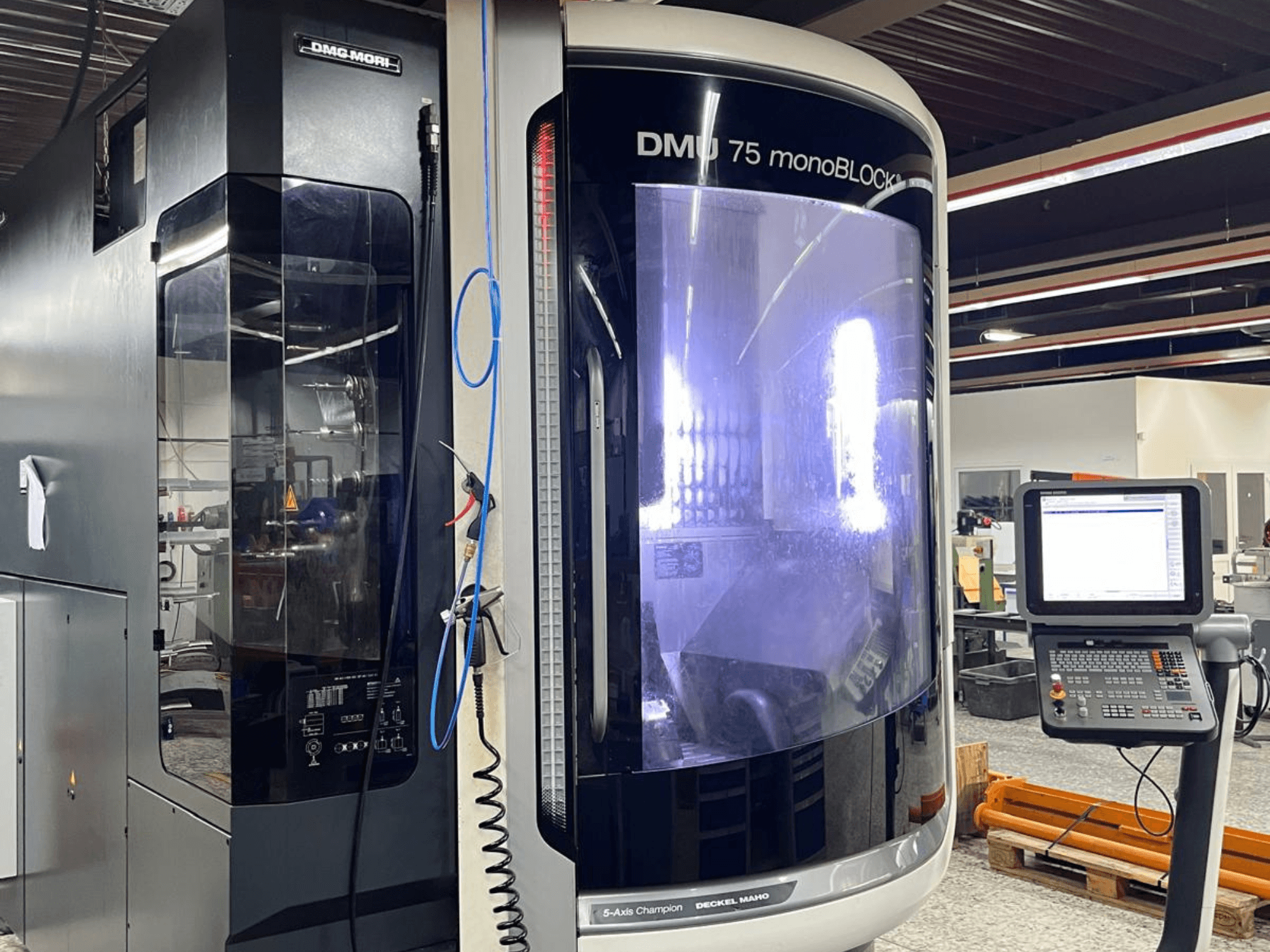Centro di lavoro universale DMG MORI DMU 75 MonoBlock, vista frontale, con pannello di controllo e involucro distintivo.