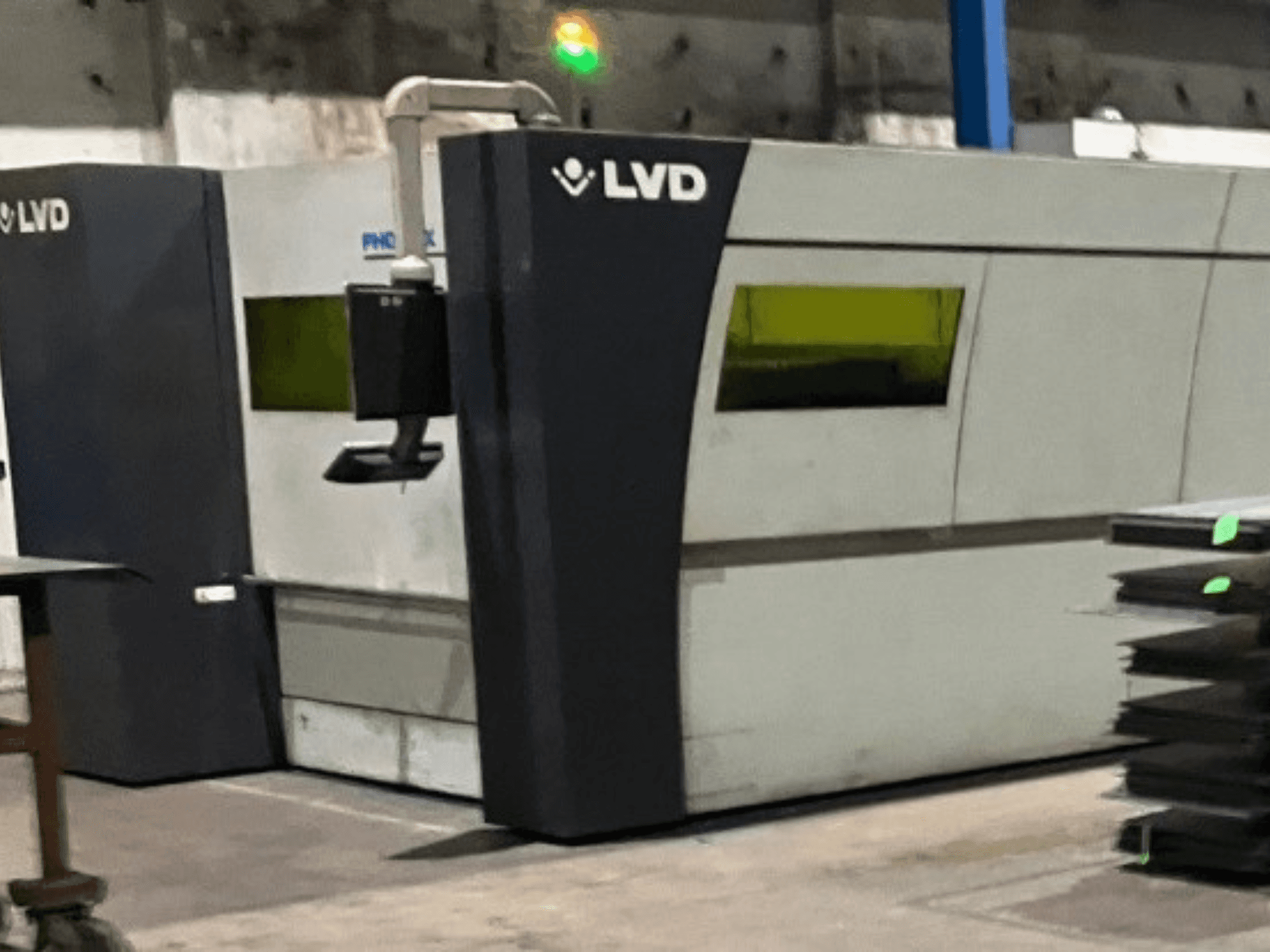 Macchina da taglio laser industriale LVD in una fabbrica, vista frontale che mostra il suo design elegante e le spie verdi di funzionamento.
