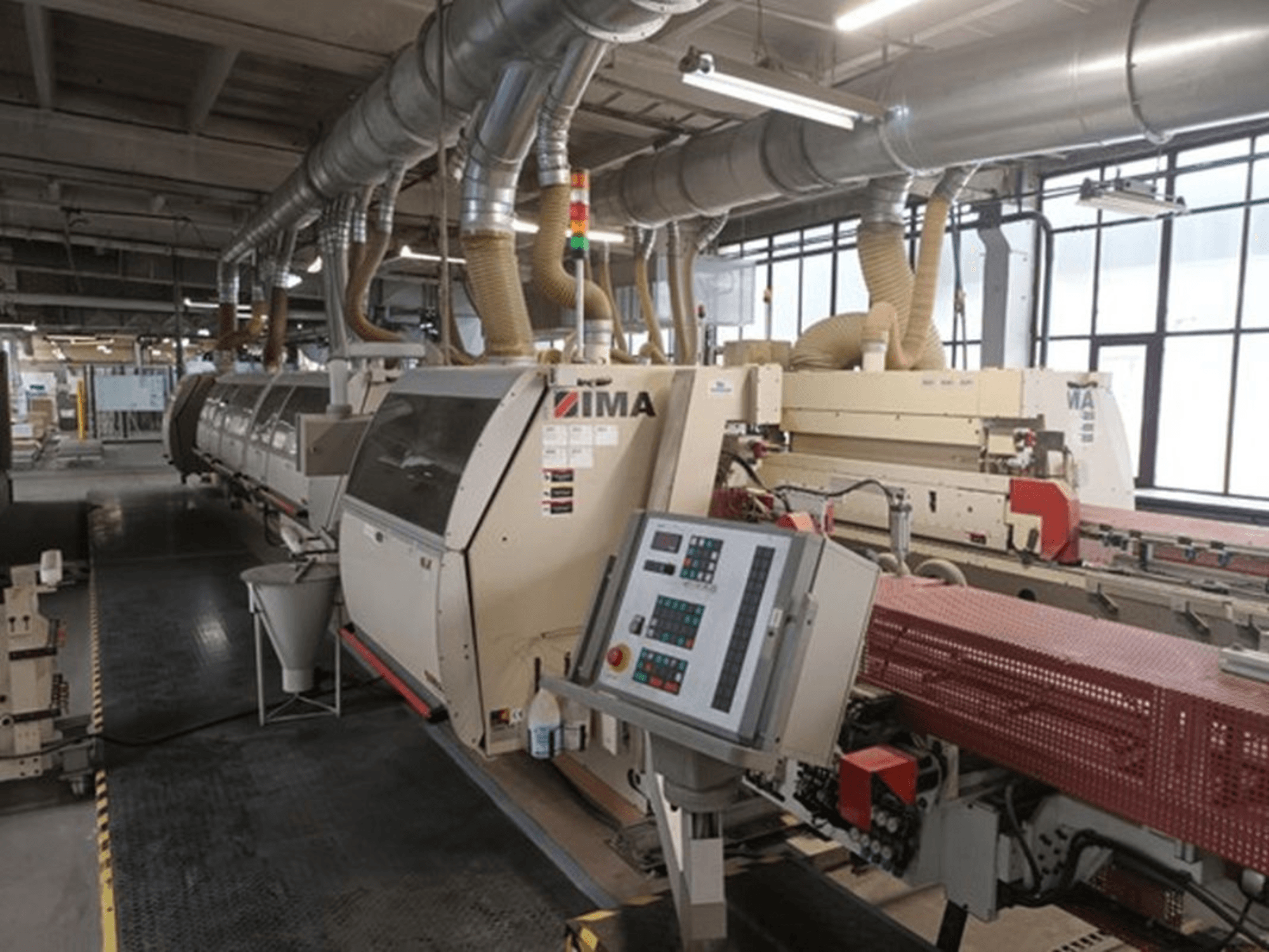 Macchine industriali IMA in un ambiente industriale, vista frontale, con pannelli di controllo e tubi di aspirazione.