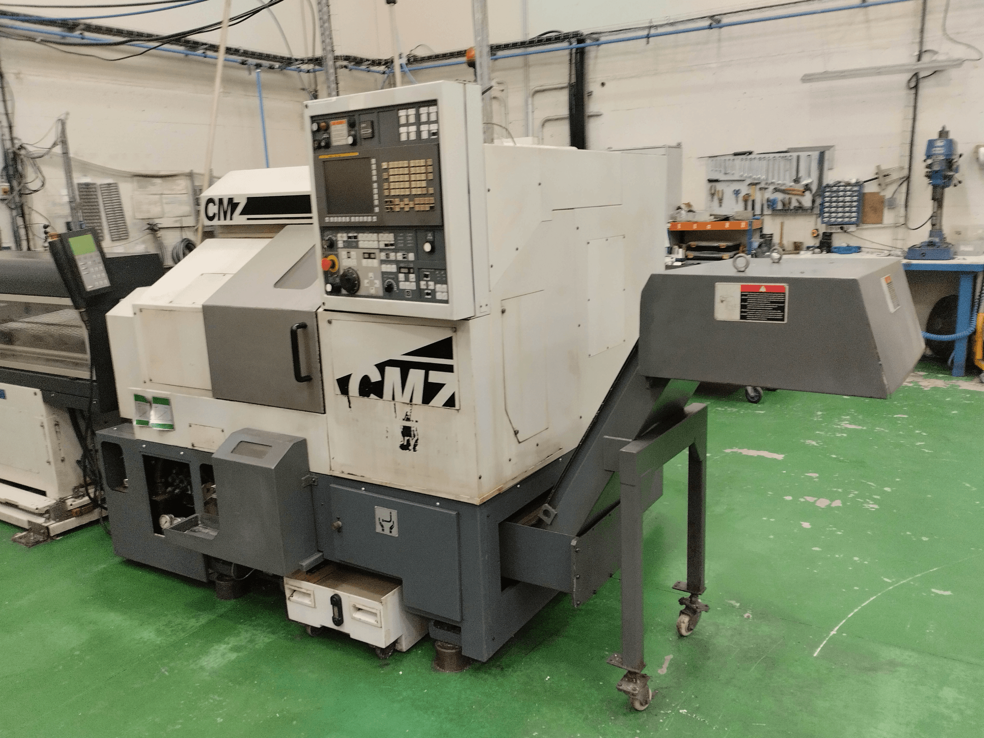 Centro di tornitura CMZ TB-67M in vista frontale, con pannello di controllo e meccanismo di alimentazione, ambientato in un'officina.
