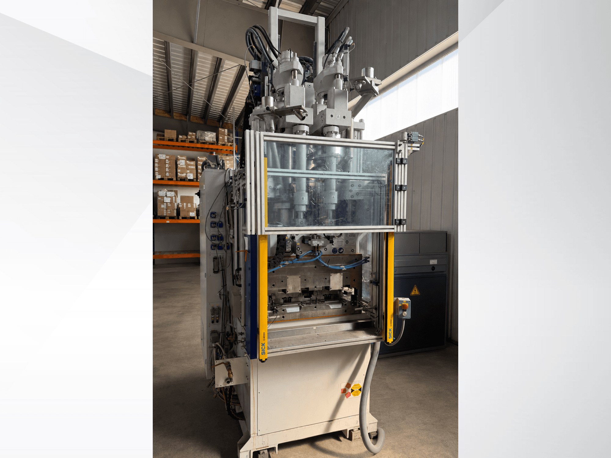 Macchina per lo stampaggio a iniezione verticale Battenfeld CM 40, vista frontale con pannello trasparente, che mostra il pannello di controllo e i componenti di iniezione.