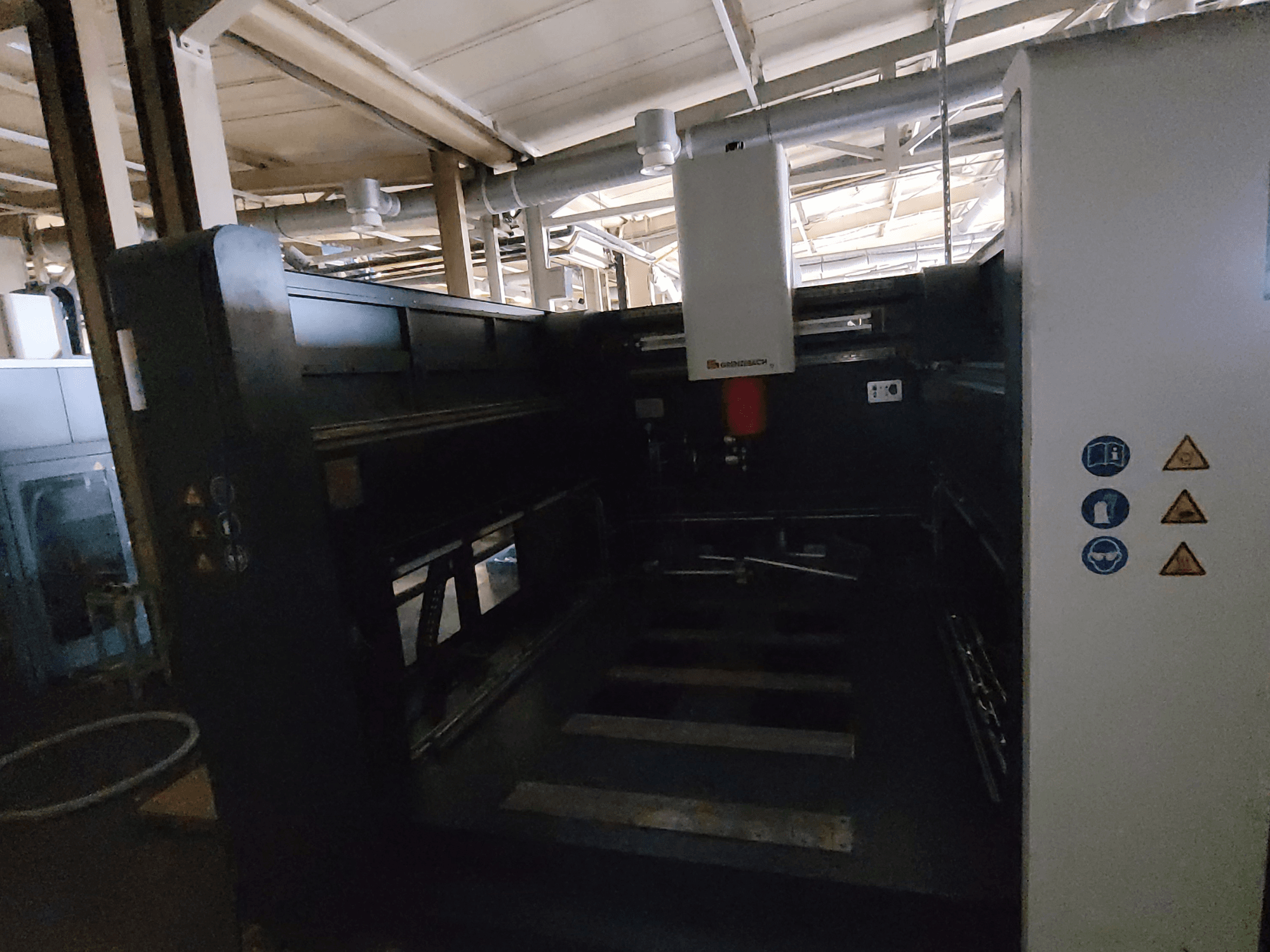 Macchina FSW GRENZEBACH modello DSM 3000, vista laterale che mostra i comandi, i simboli di sicurezza e l'area di lavoro destinata alle operazioni di lavorazione.