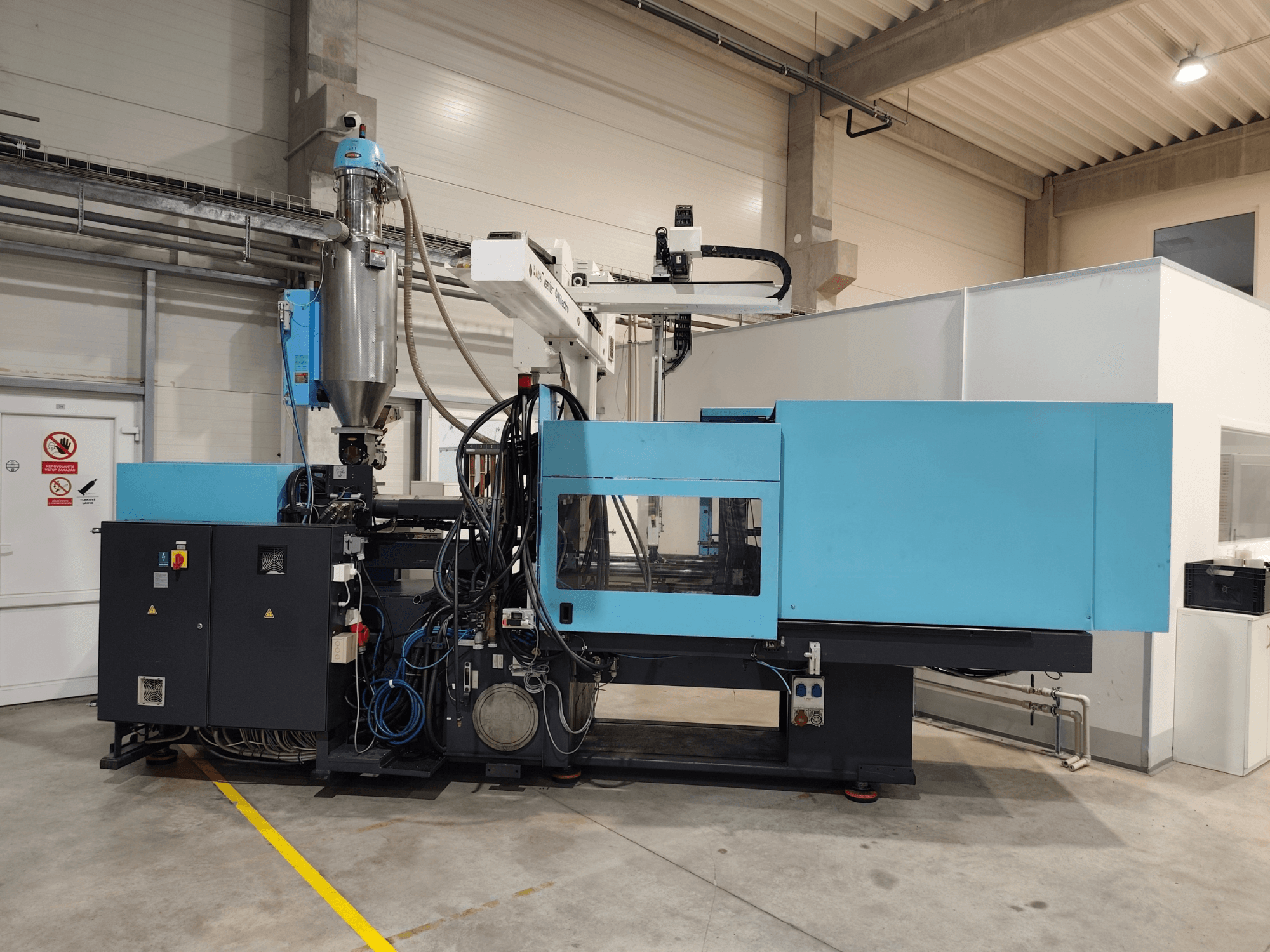 Vista frontale di una pressa a iniezione idraulica DEMAG Ergotech Extra 160-430 con pannello di controllo e tramoggia in primo piano.