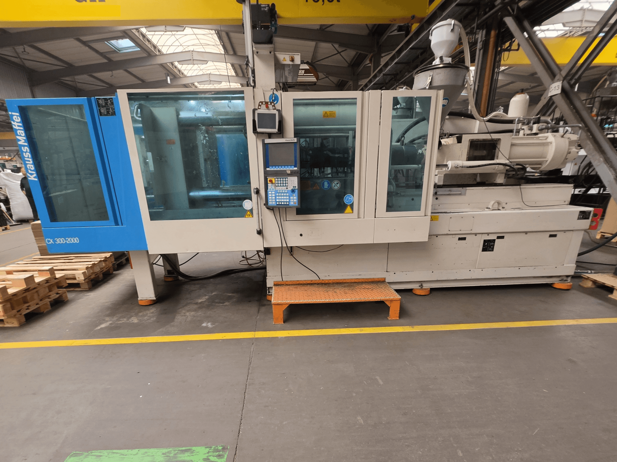 Pressa a iniezione idraulica Krauss Maffei 300-2000 CX, vista laterale che mostra il pannello di controllo e le ampie finestre.