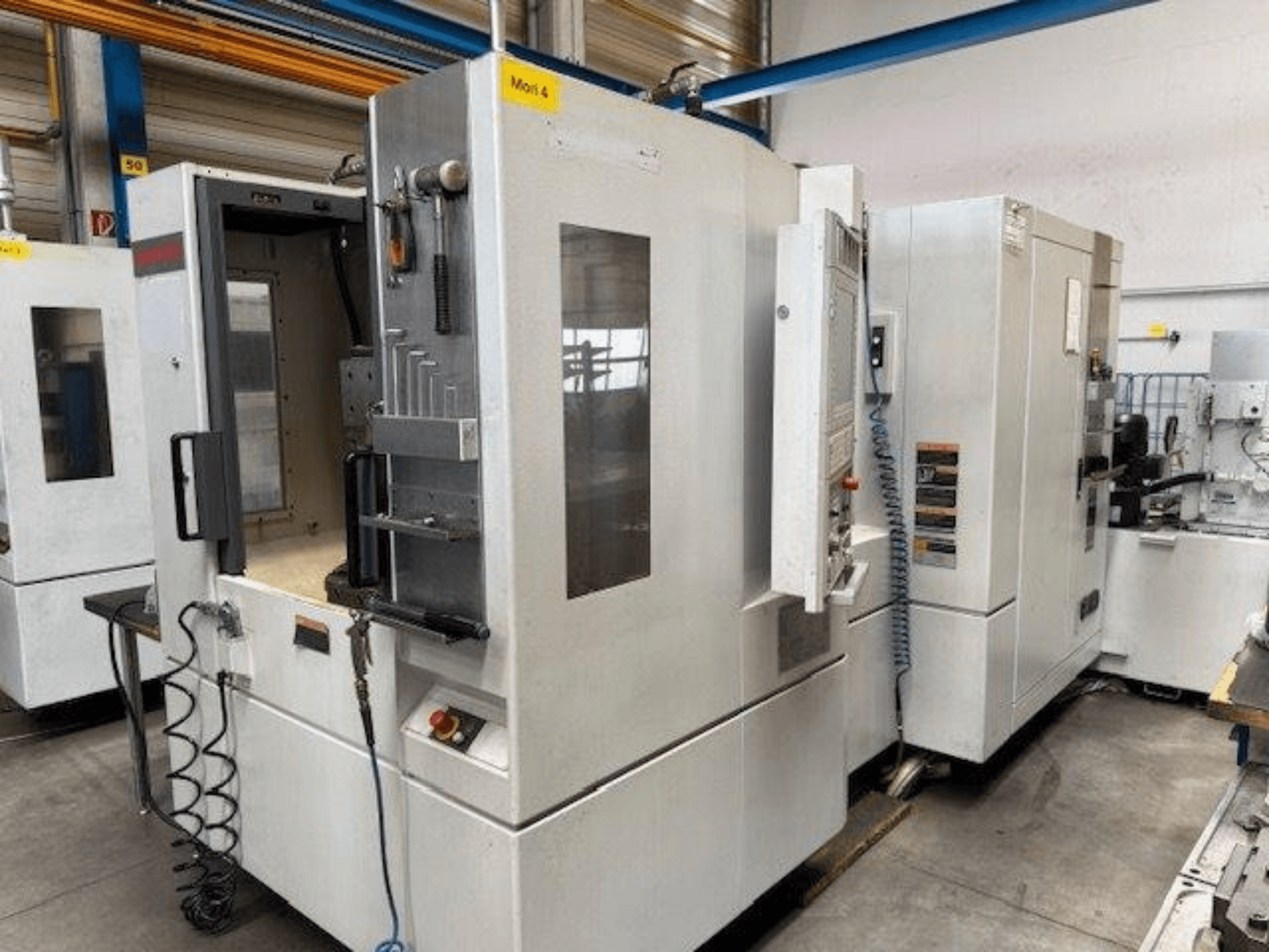 Centro di lavoro orizzontale MORI SEIKI NH4000 DCG visto frontalmente, con porta aperta e dettagli del pannello di controllo.