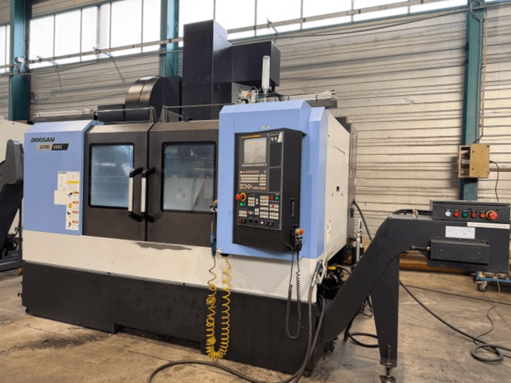 Fresatrice CNC Doosan DNM 500II in vista frontale, con pannello di controllo e portautensili, in un ambiente di fabbrica.