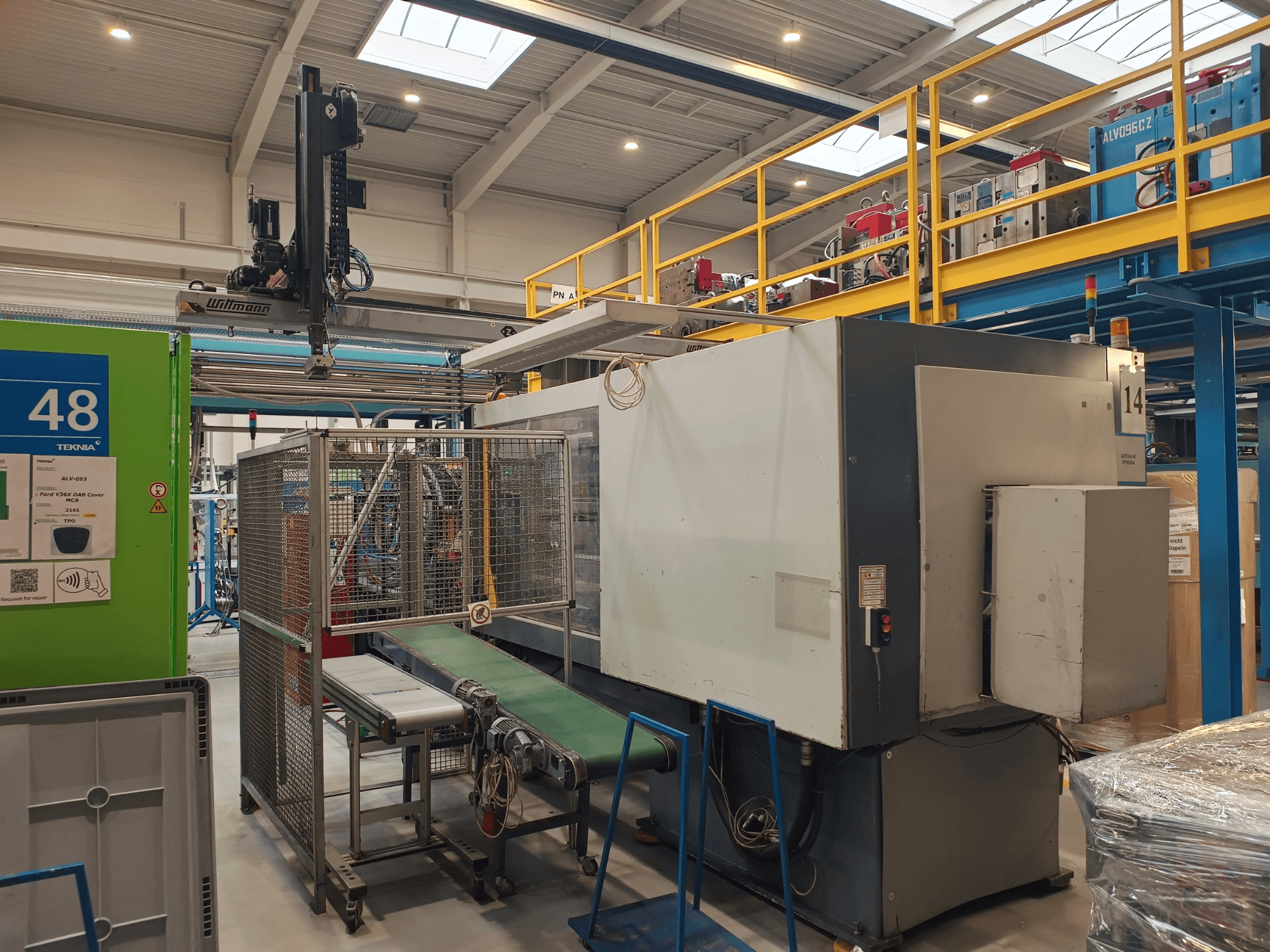 Macchina per l'automazione industriale di Winmon, vista laterale che mostra il nastro trasportatore, il pannello di controllo e la gabbia di sicurezza in un ambiente industriale.