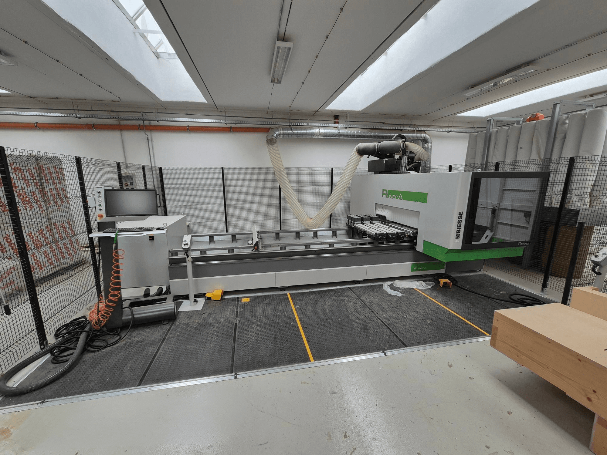 Biesse Rover Una macchina CNC in un'officina, vista frontale. Presenta un pannello di controllo, un sistema di aspirazione e una superficie di lavoro.