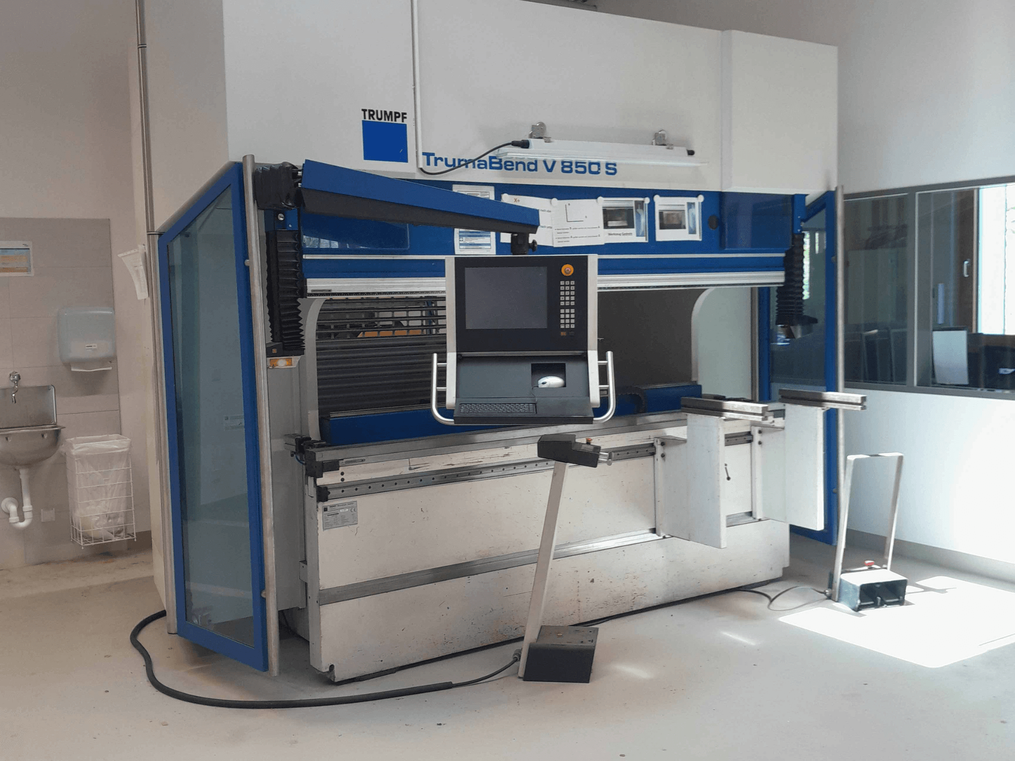 Piegatrice TRUMPF TrumaBend V 850 S, vista frontale con pannello di comando e dispositivi di sicurezza in un ambiente di lavoro ben illuminato.