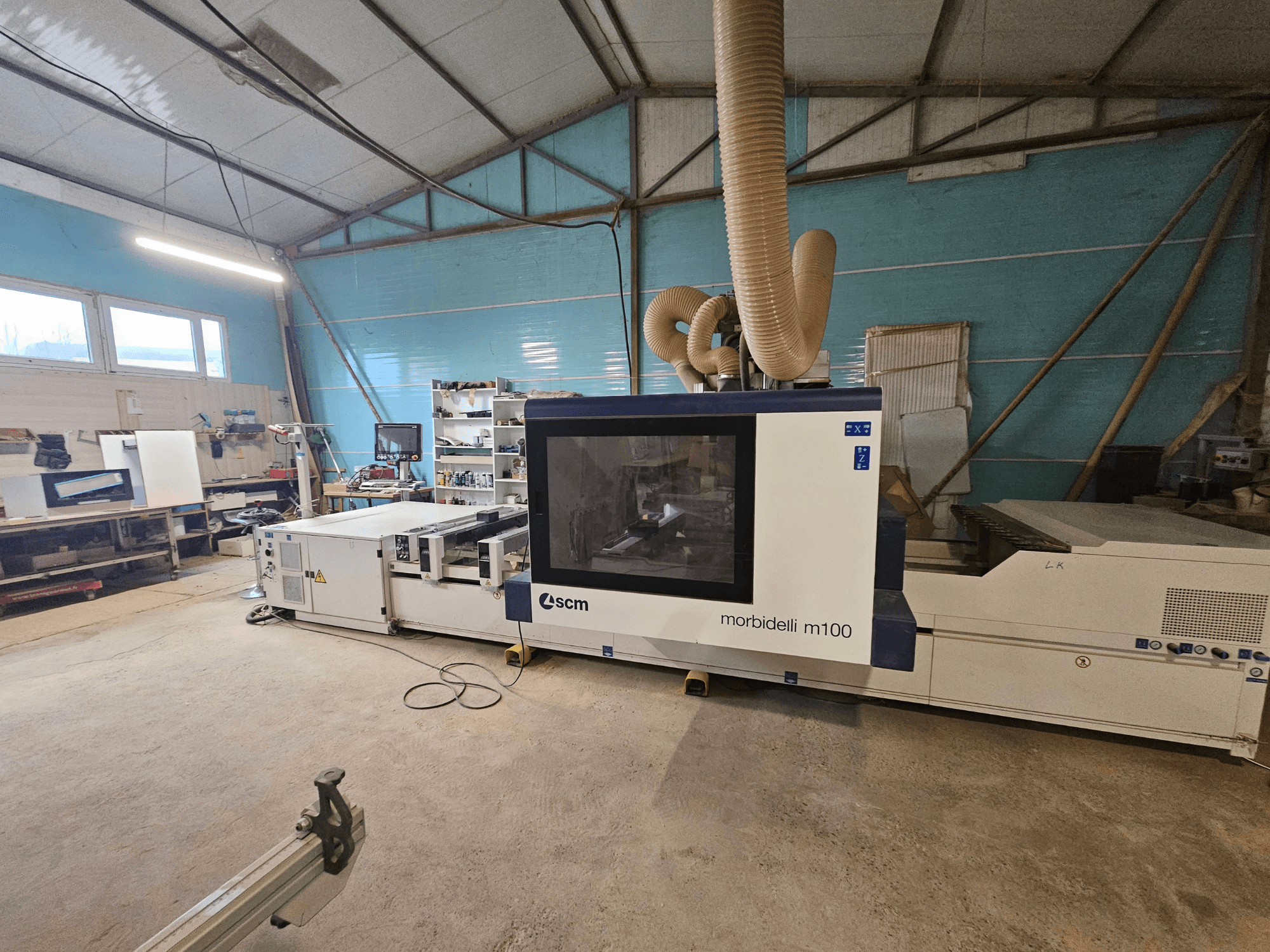 Macchina CNC SCM Morbidelli M100 in officina, vista frontale, con sistema di aspirazione della polvere e pannello di controllo.