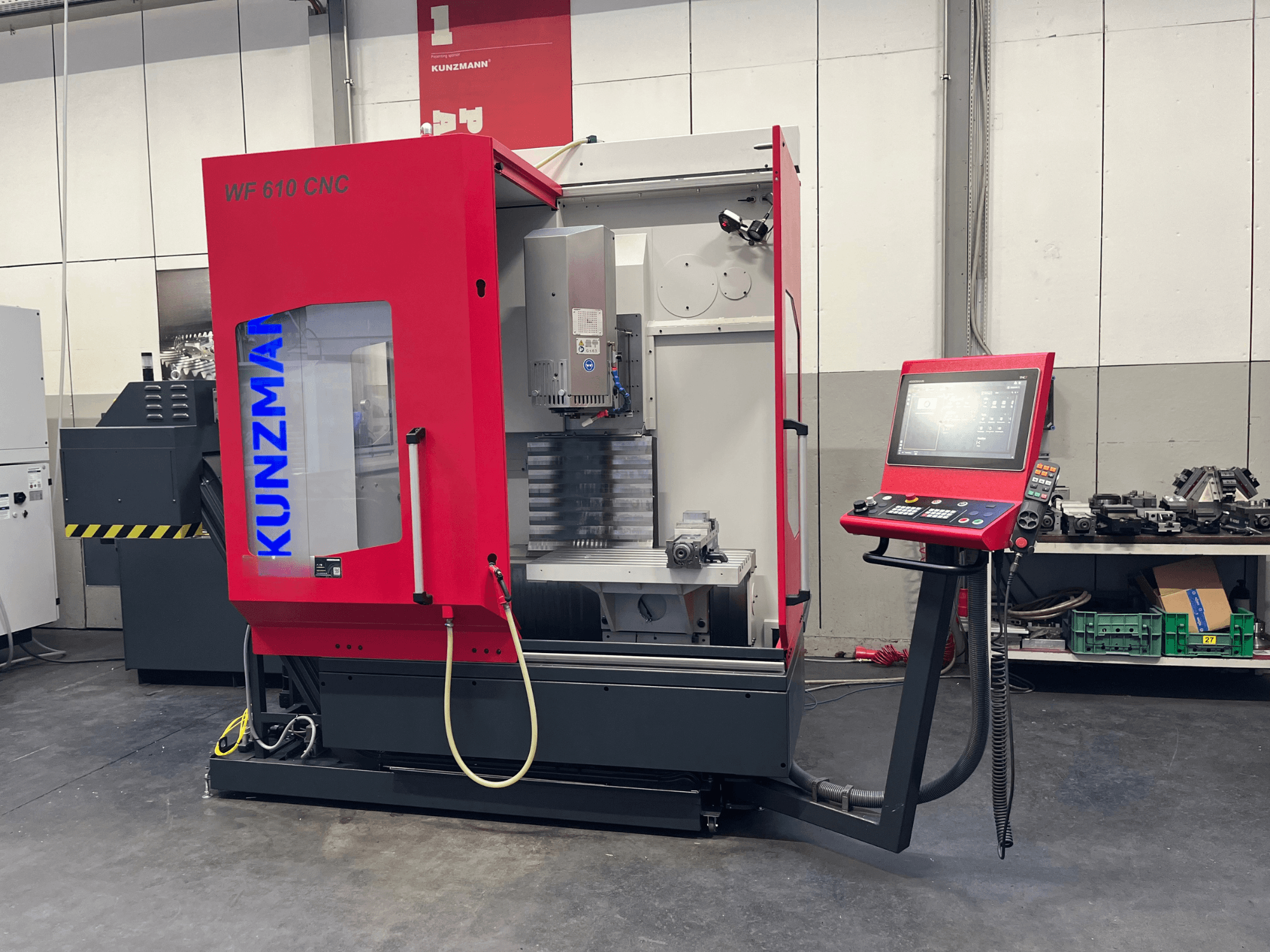 Centro di lavorazione verticale CNC KUNZMANN WF 610 in un'officina, con pannello di controllo e componenti della macchina in vista.