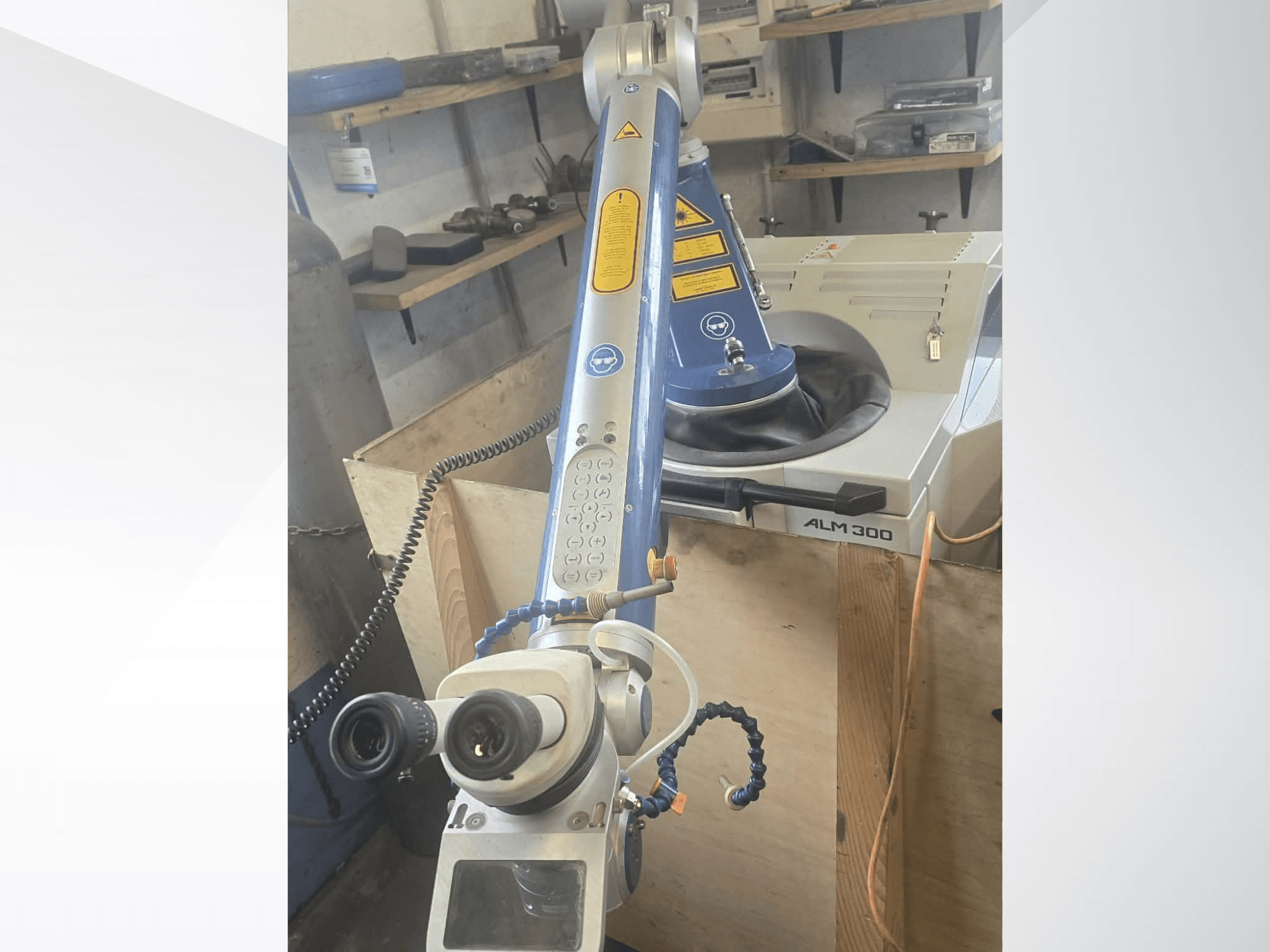 Vista frontale della saldatrice laser ALPHA LASER ALM 300, dotata di braccio robotico, lenti ottiche e pannello di controllo.