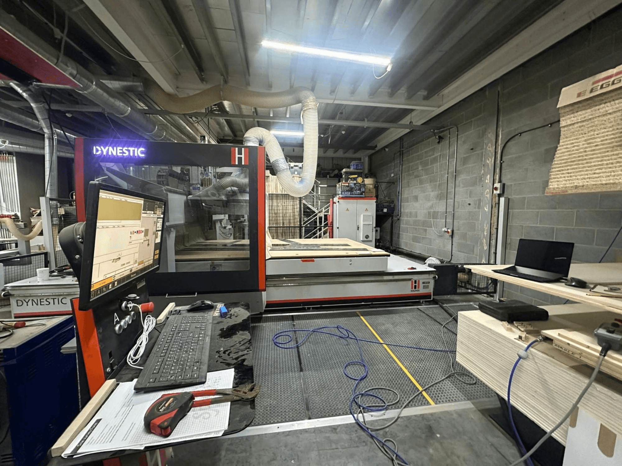 Mulino per legno HOLZHER Dynestic 7535 in officina, con pannello di controllo, monitor e materiali sul tavolo di lavoro, vista frontale.