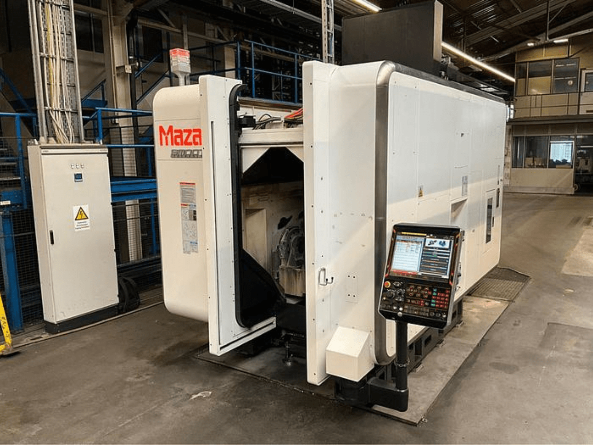 Macchina CNC Maza vista frontalmente, con pannello di controllo, design industriale e componenti del macchinario visibili.