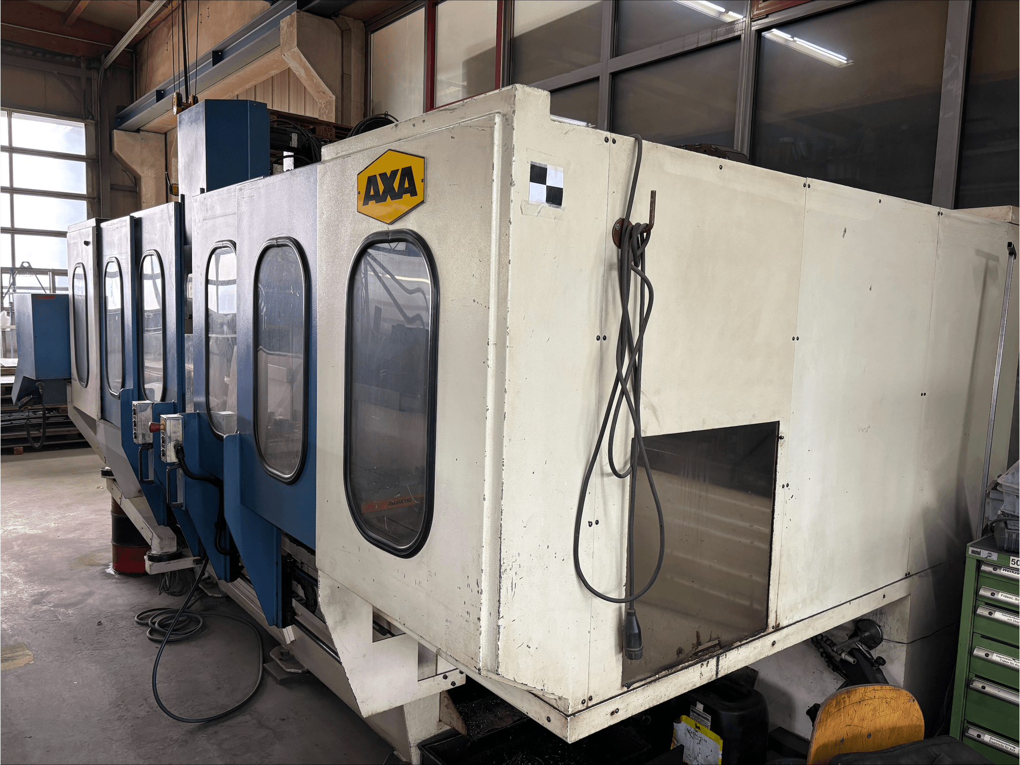 Centro di lavoro verticale AXA VSC-1-M/C, vista frontale, con grande armadio bianco e pannello di controllo blu.