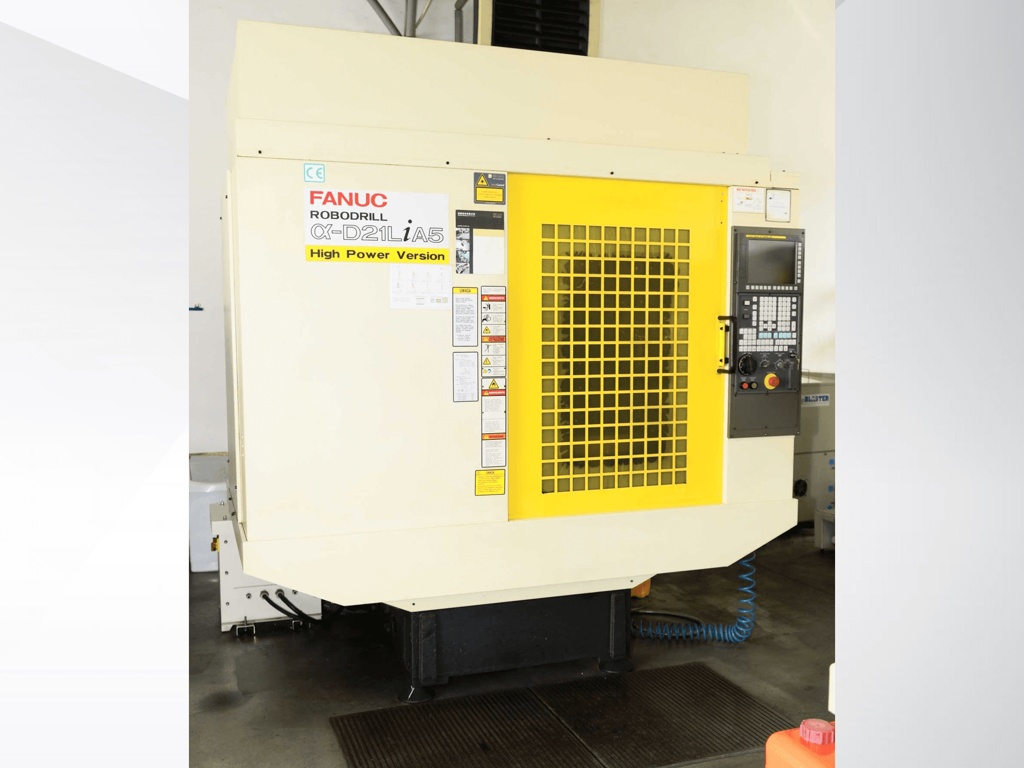 Centro di lavorazione verticale FANUC ROBODRILL α-D21LiA5, vista frontale con griglia di sicurezza gialla e dettagli del pannello di controllo.