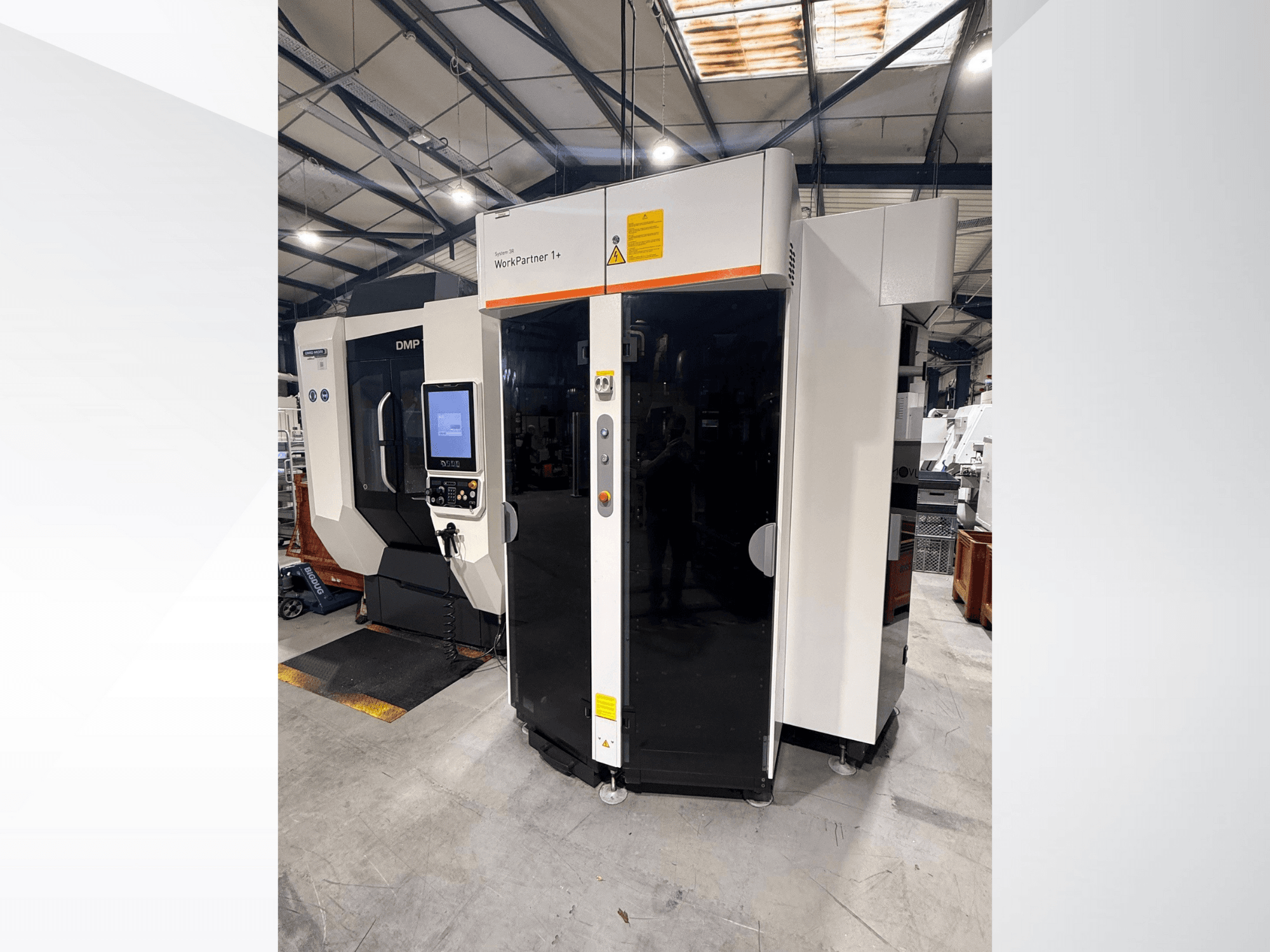 DMP WorkPartner 1+, vista frontale; presenta un pannello touchscreen e indicatori di sicurezza in un ambiente di produzione.