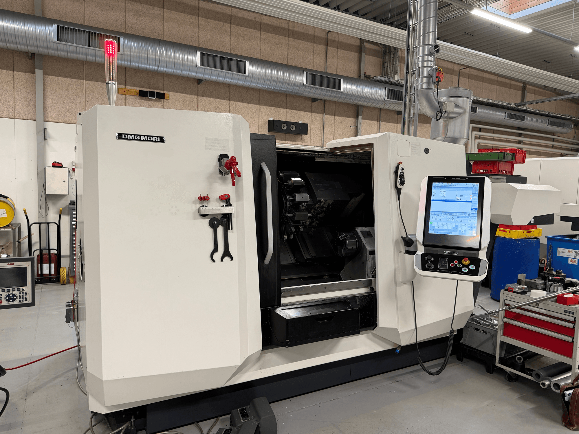 Tornio orizzontale DMG MORI CLX 450 V6, vista frontale con pannello di controllo, pulsante di arresto di emergenza e spia di sicurezza visibili.