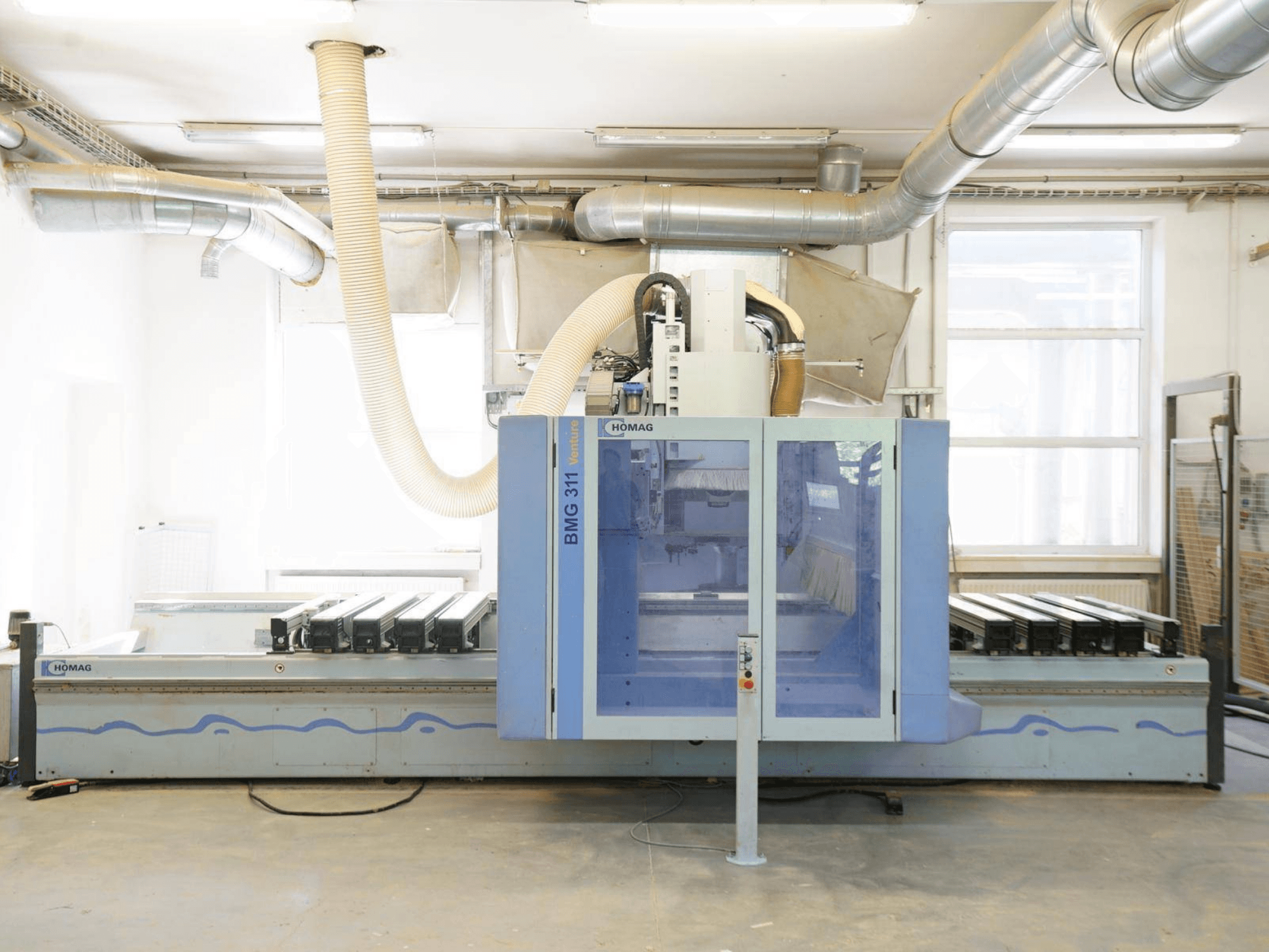 Centro di lavorazione del legno a controllo numerico HOMAG V BMG 311/42/F/K, vista frontale, dotato di ampio piano di lavoro e sistema di aspirazione delle polveri.