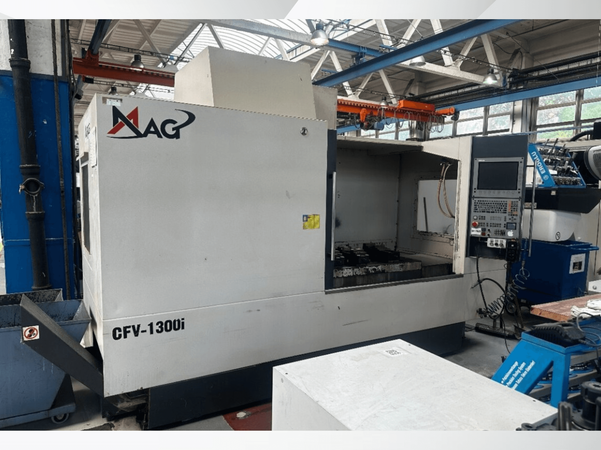 Centro di lavorazione verticale Cincinnati MAG CFV1300i in un'officina, vista frontale che mostra il pannello di controllo e l'interno della macchina.