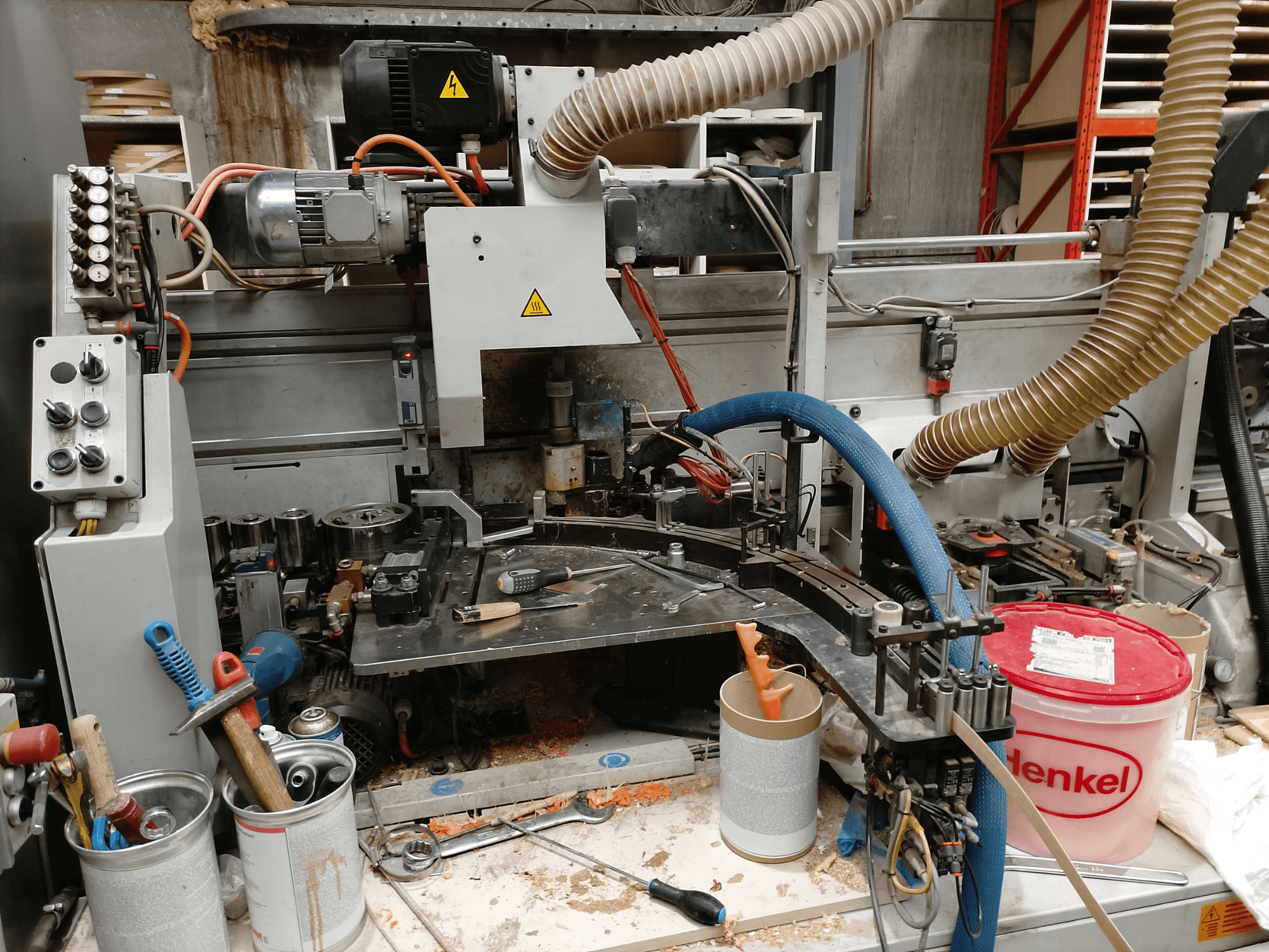 Bordatrice BIESSE Edge Stram B1 in vista frontale, con macchinari, tubi e strumenti di lavoro in mezzo ai trucioli di legno.