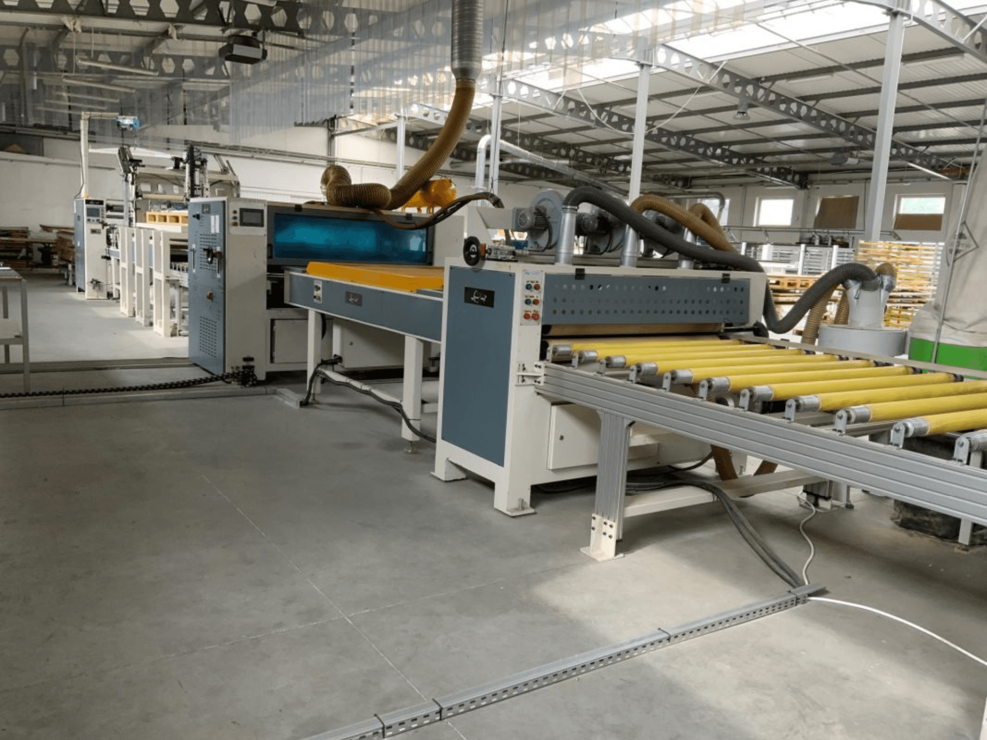 Pressa di laminazione MASTER PUR-1400 in un ambiente industriale, vista frontale, con in primo piano i rulli e i comandi operativi.