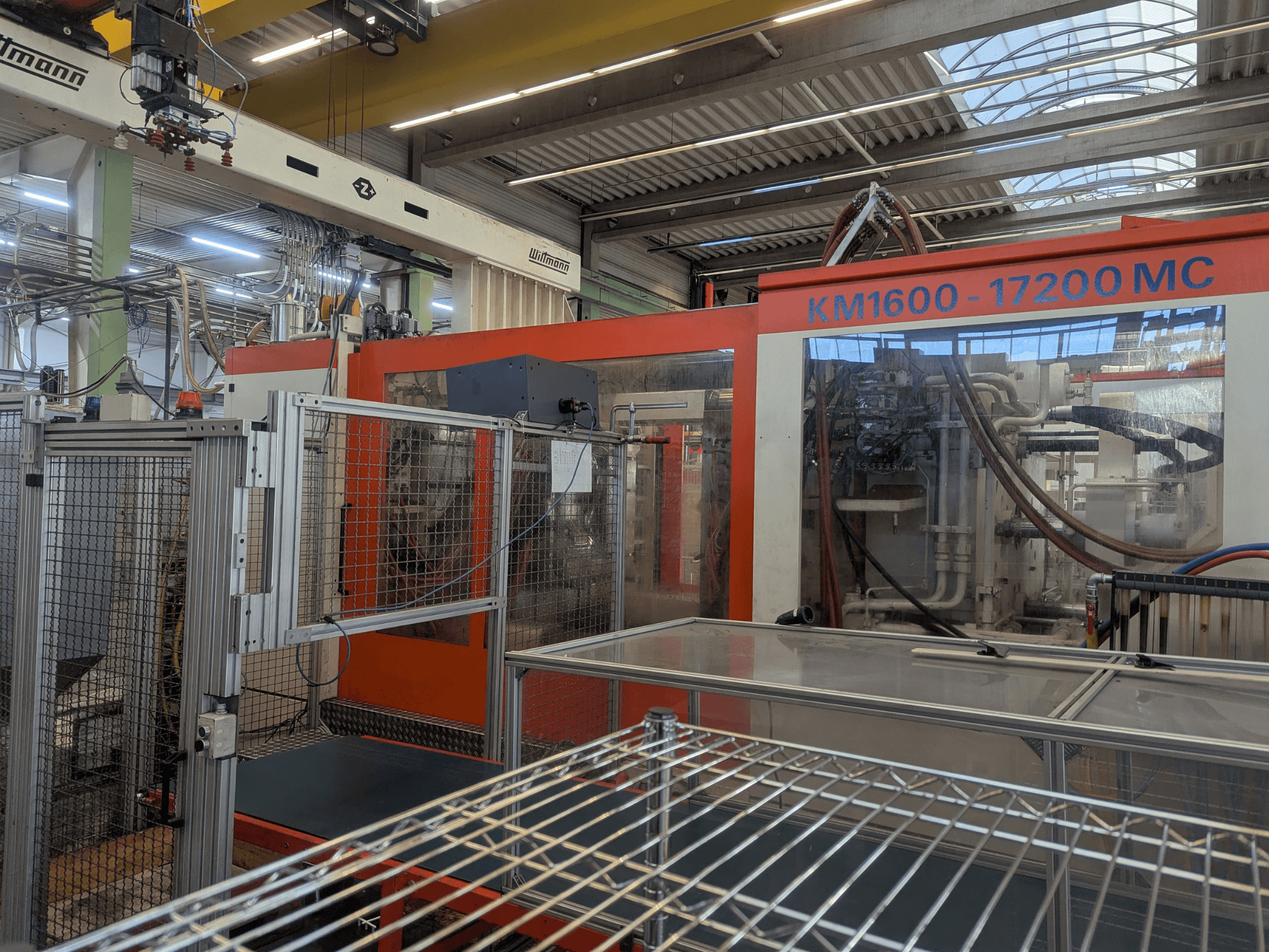 Pressa a iniezione idraulica Krauss Maffei KM 1600-17200MC, vista frontale con pannello di controllo e linee idrauliche visibili.