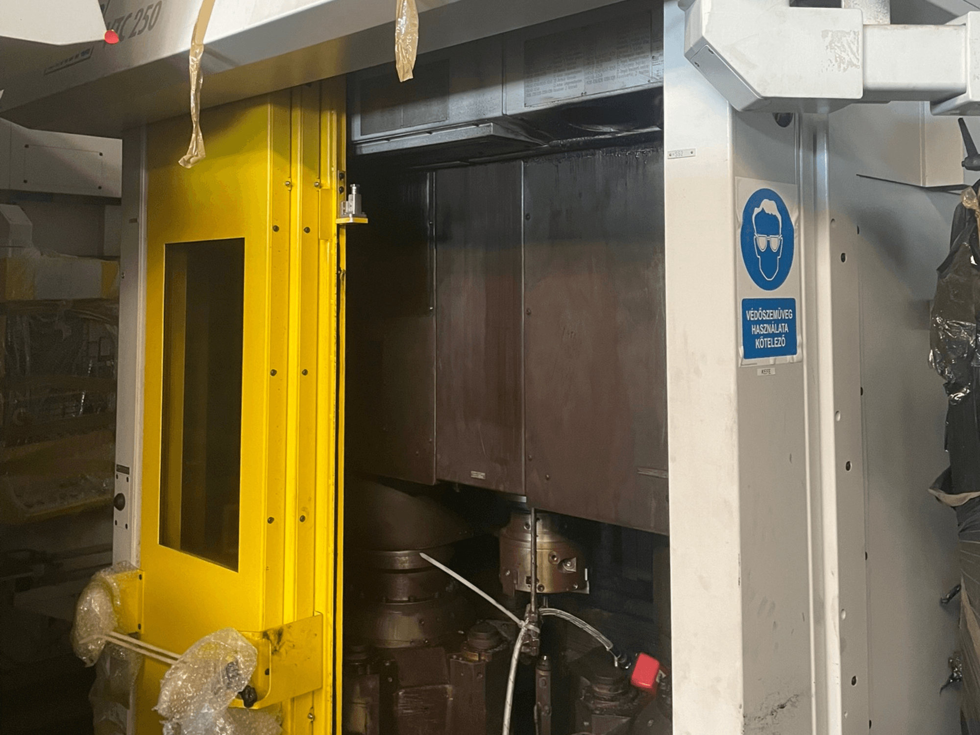 Porta d'ingresso gialla di una macchina con cartello di sicurezza, vista frontale di una macchina industriale modello Z250, che mostra i componenti interni.