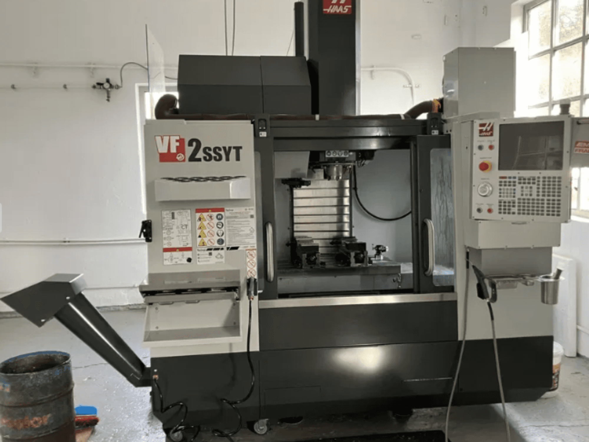 Fresatrice CNC Haas VF-2SSYT, vista frontale, con pannello di controllo, portautensili e sistema di raffreddamento per la lavorazione dei metalli.