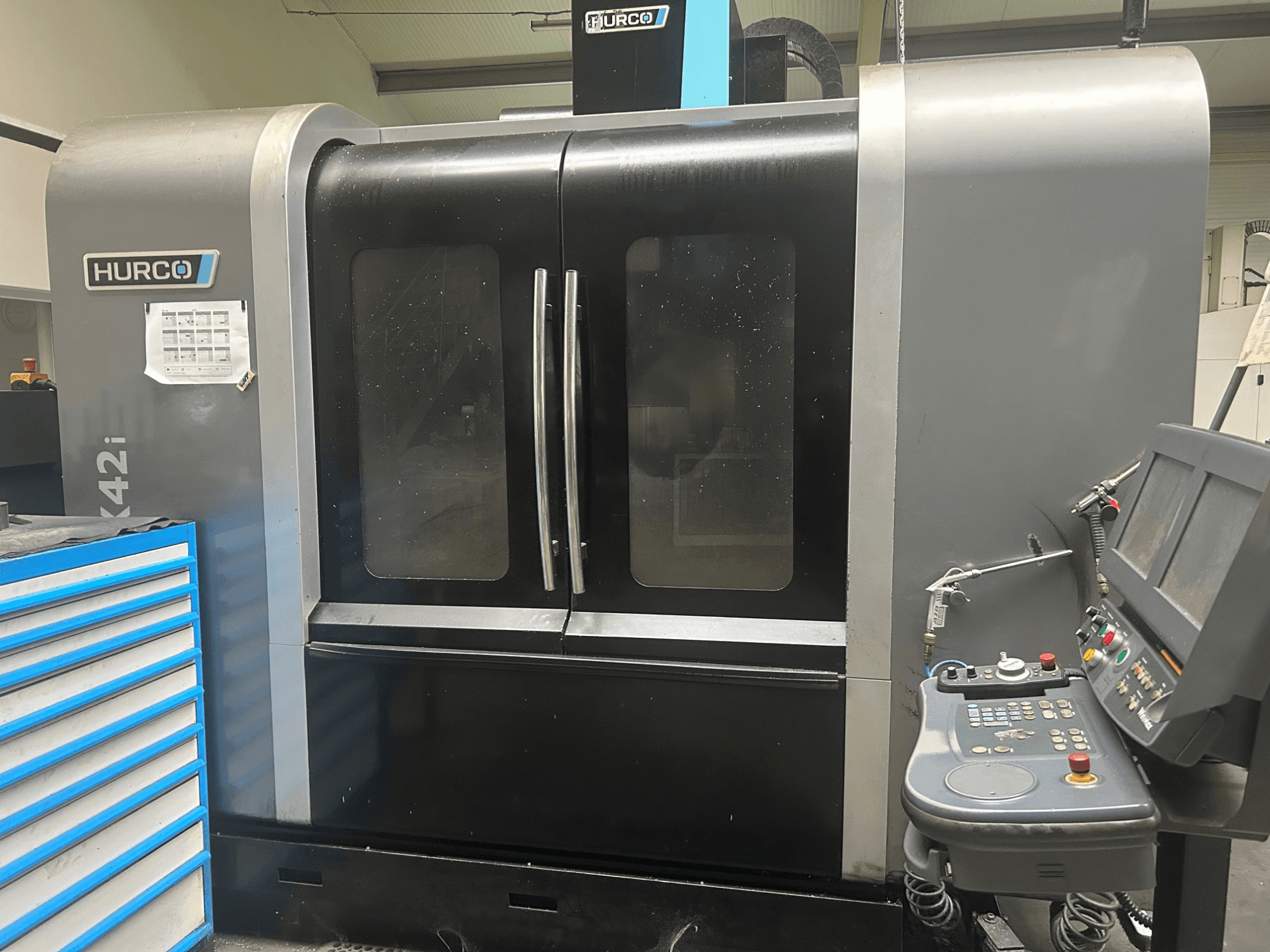 Macchina CNC Hurco VMX42i, vista frontale con pannello di controllo laterale, dotata di doppie porte e dettagli tecnici visibili.