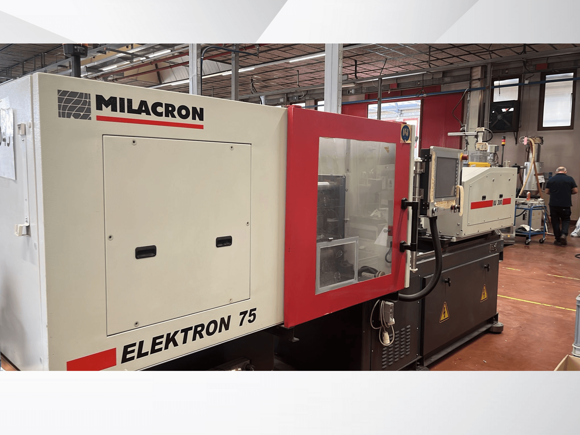 Macchina ad iniezione Milacron Elektron 75 in un'officina, vista laterale che mostra il pannello di controllo e le parti meccaniche.